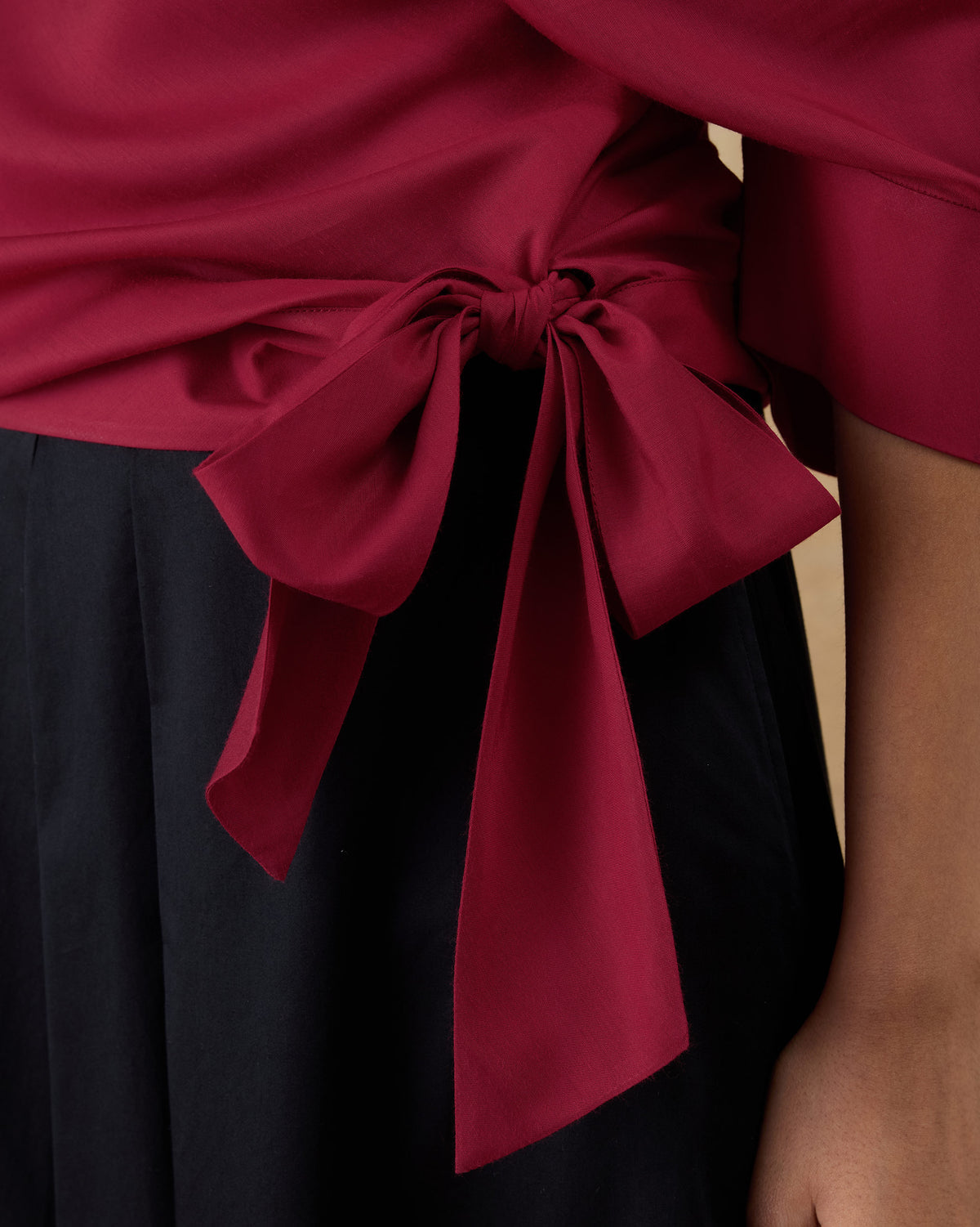 Close-up of the side waist bow on a red Tokyo off-shoulder top.