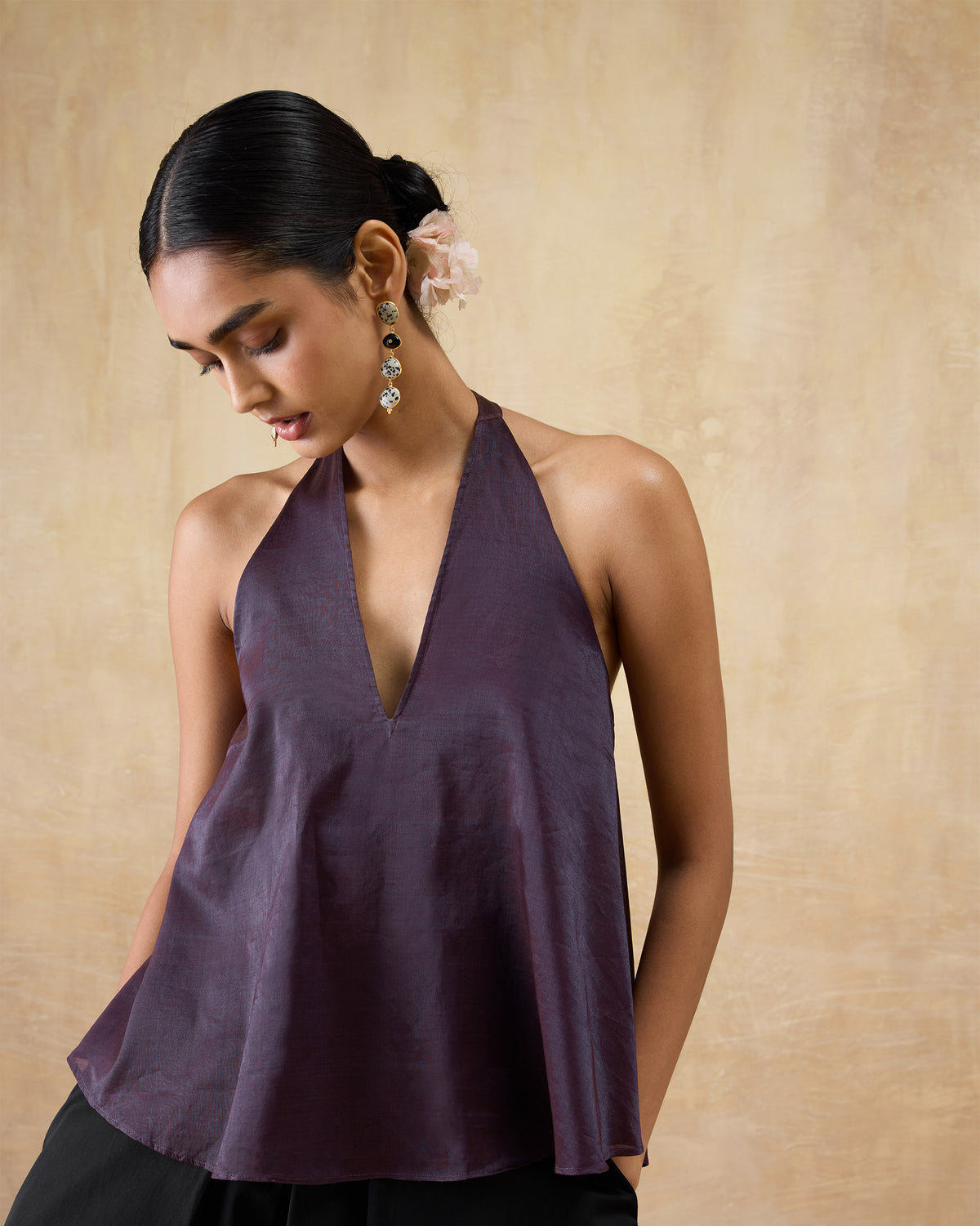 Person wearing a plum metallic A-line halter top with a deep V-neck.