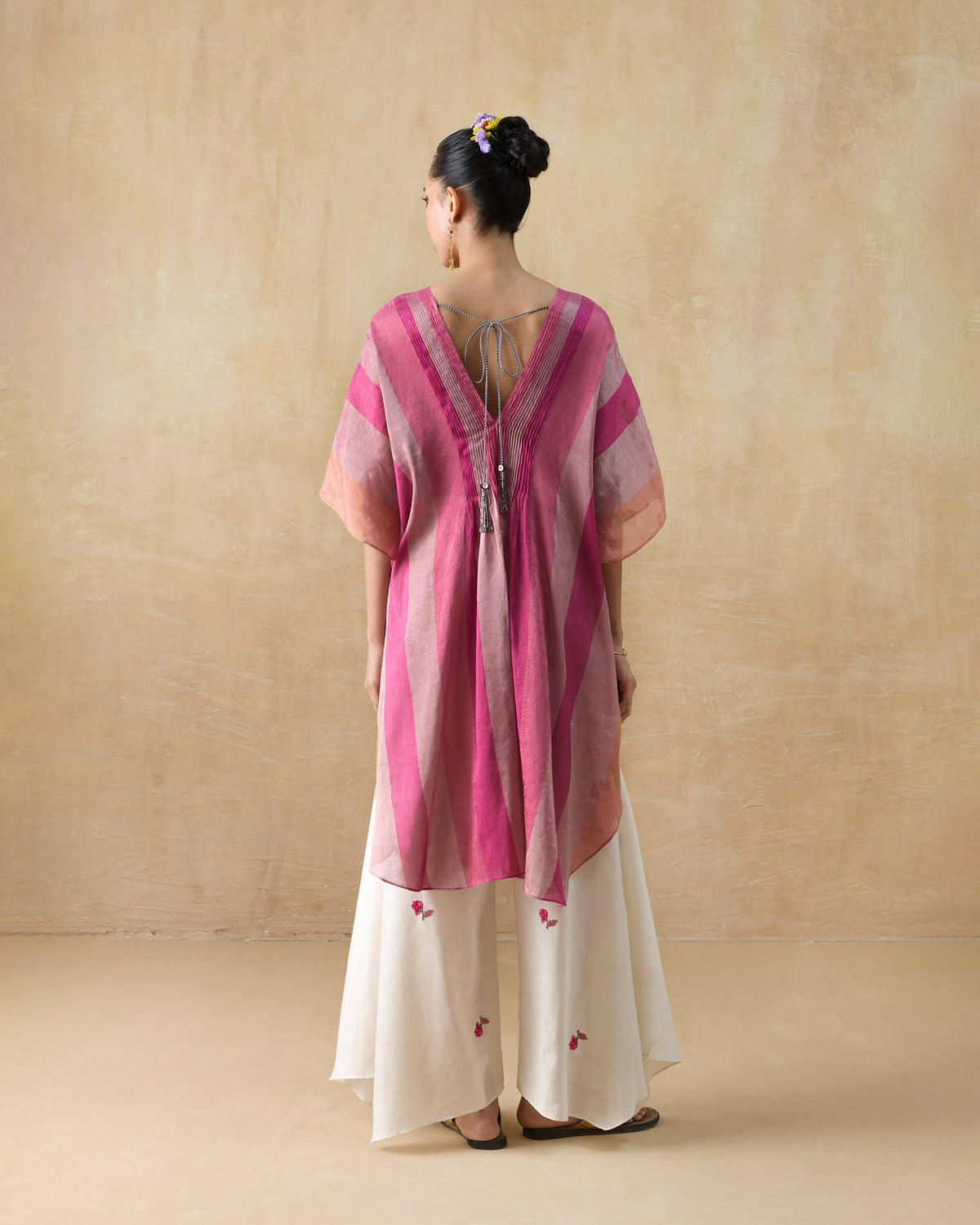 Back of a pink striped Jhilmil Kaftan with a deep V and silver tassel ties.