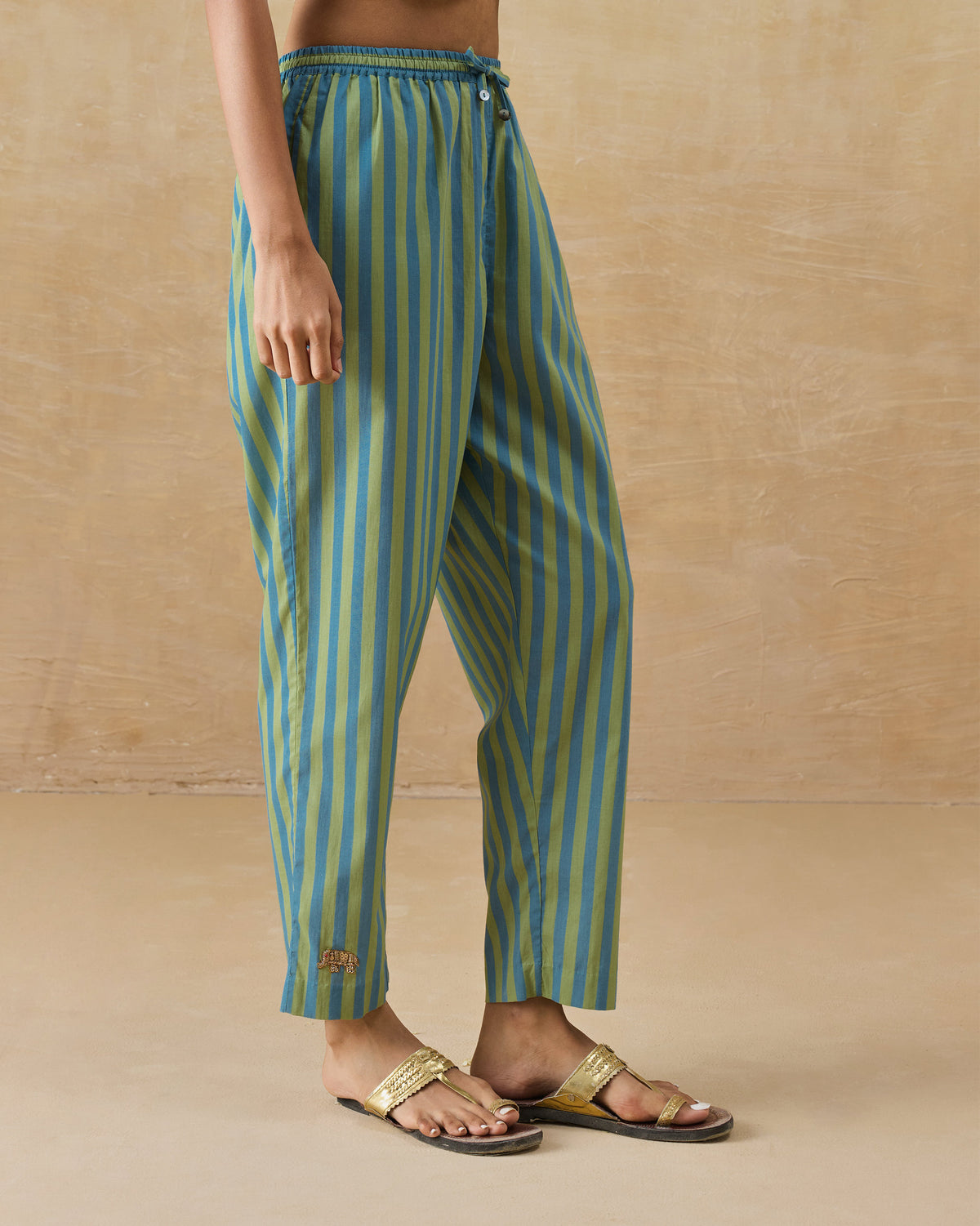 Side view of aqua striped Arzoie pants showing the narrow leg.