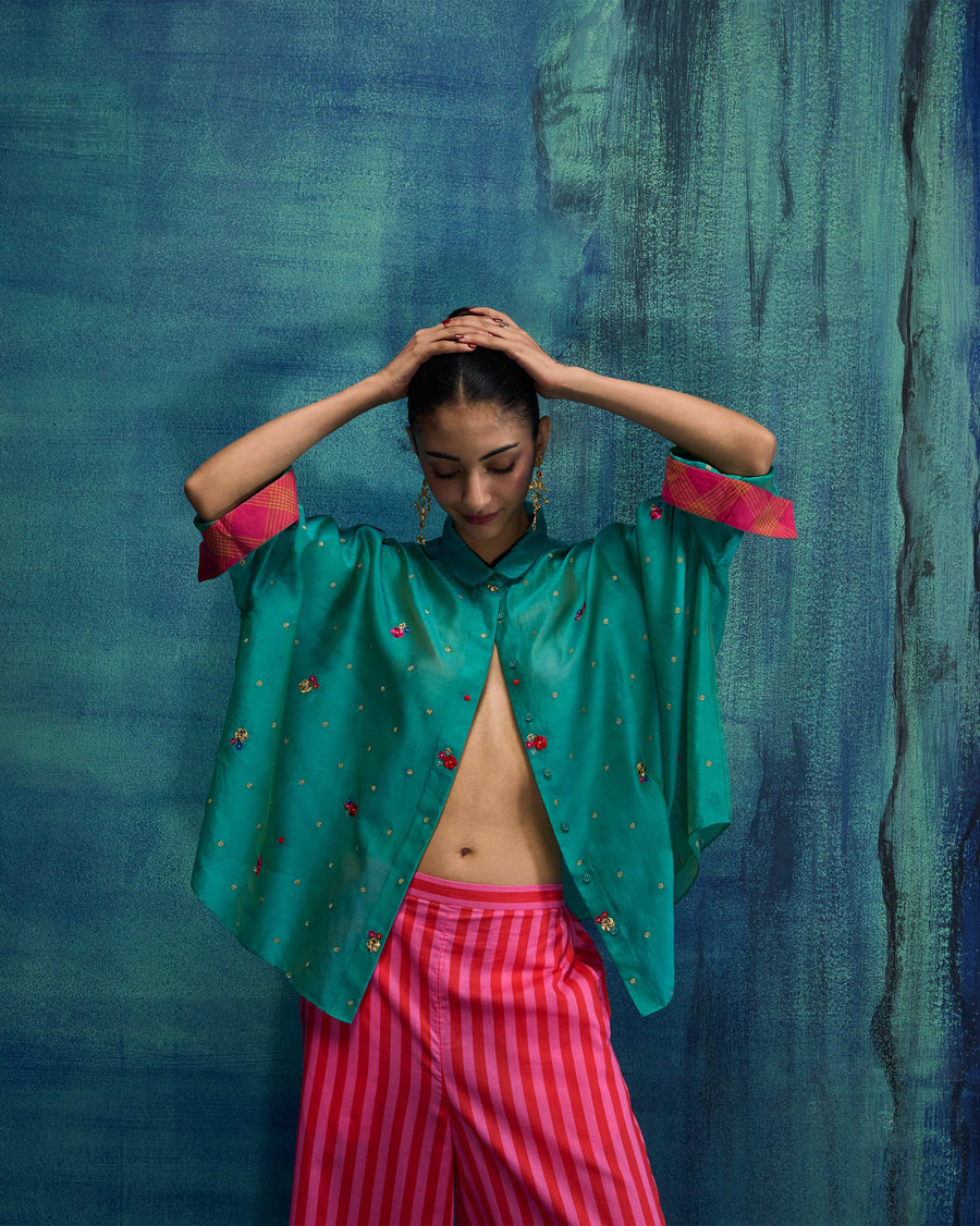 The Boxy Shirt worn loose over striped Basic Pyjamas against a blue backdrop.