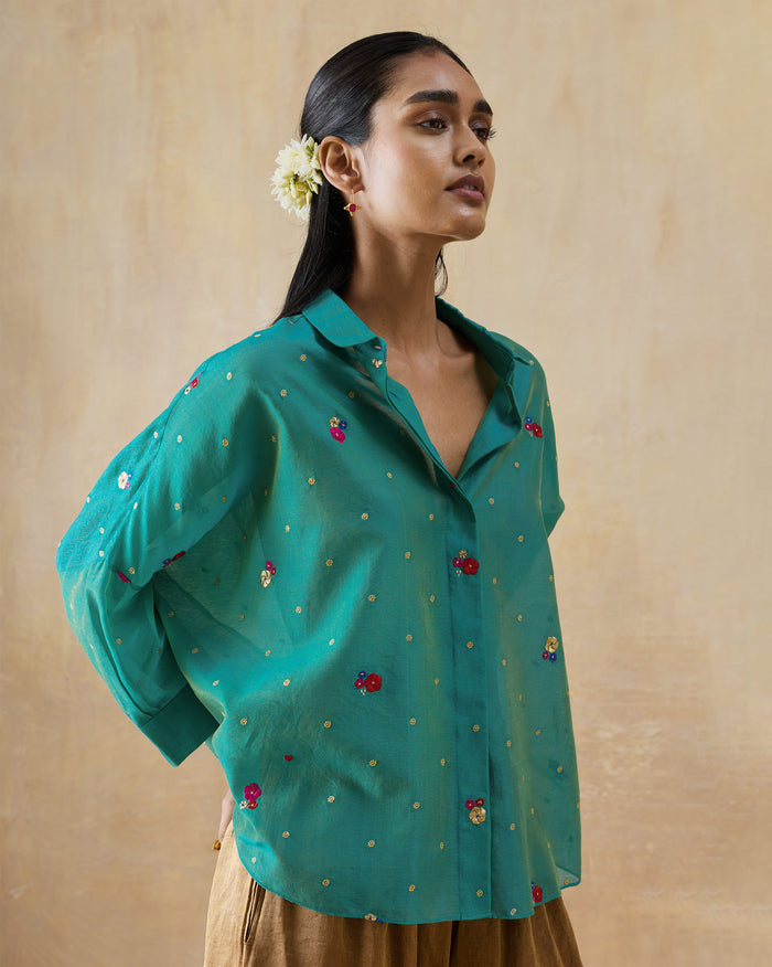 Side view of an aqua Boxy shirt with gold dots and floral embroidery.