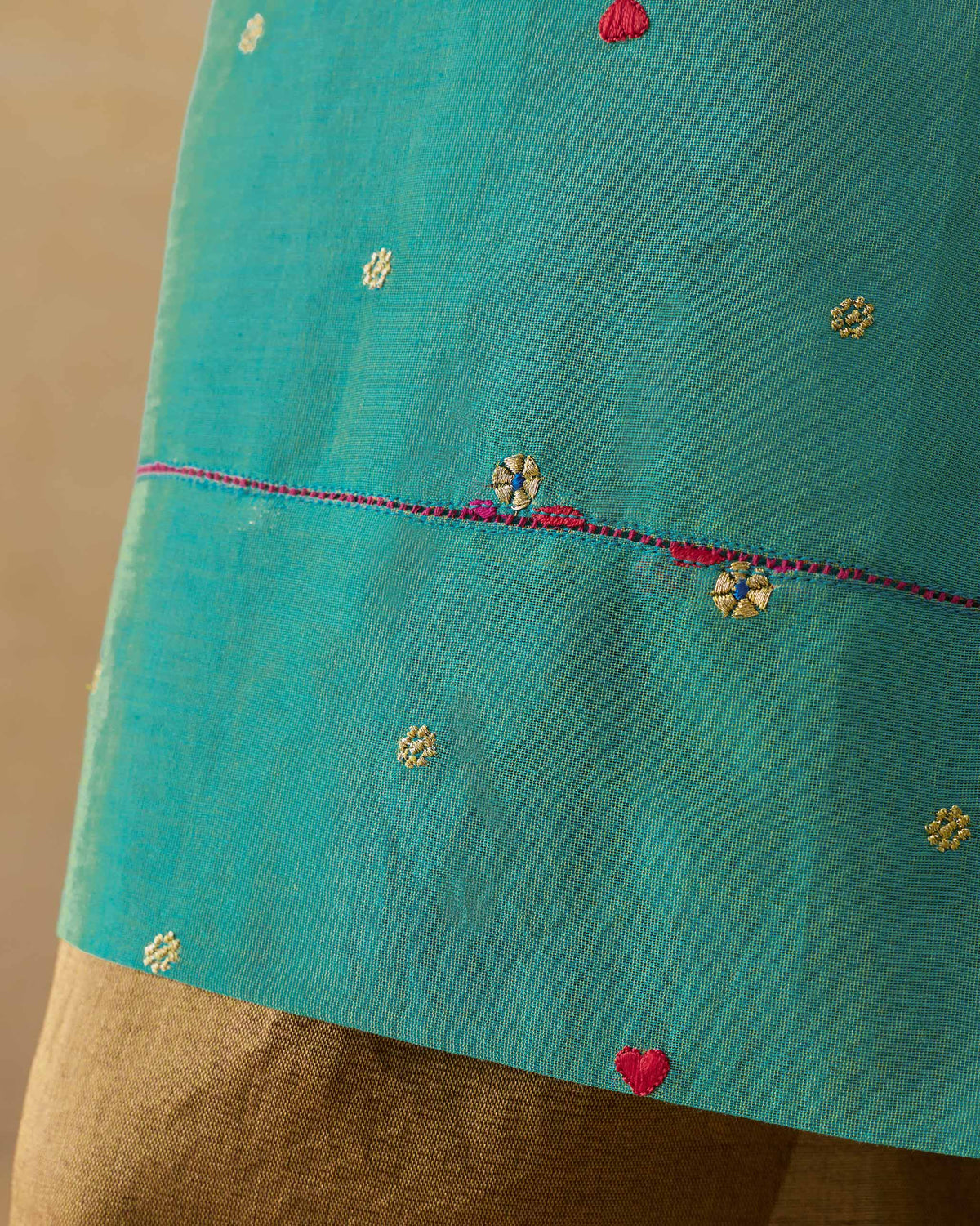 Close-up of an aqua Twilight kurta showing floral embroidery at the hem.