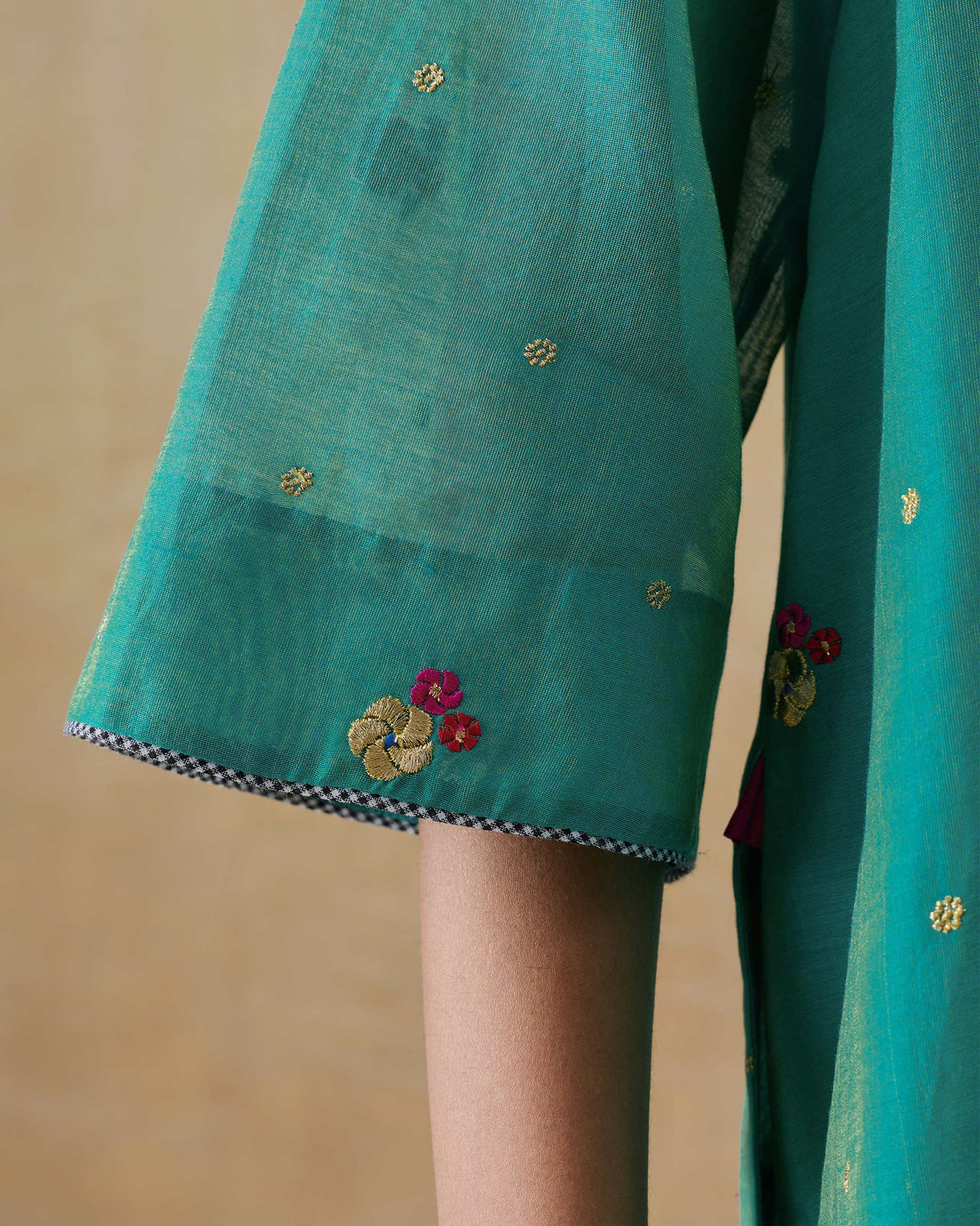 Close-up of an aqua Twilight kurta sleeve showing floral embroidery.