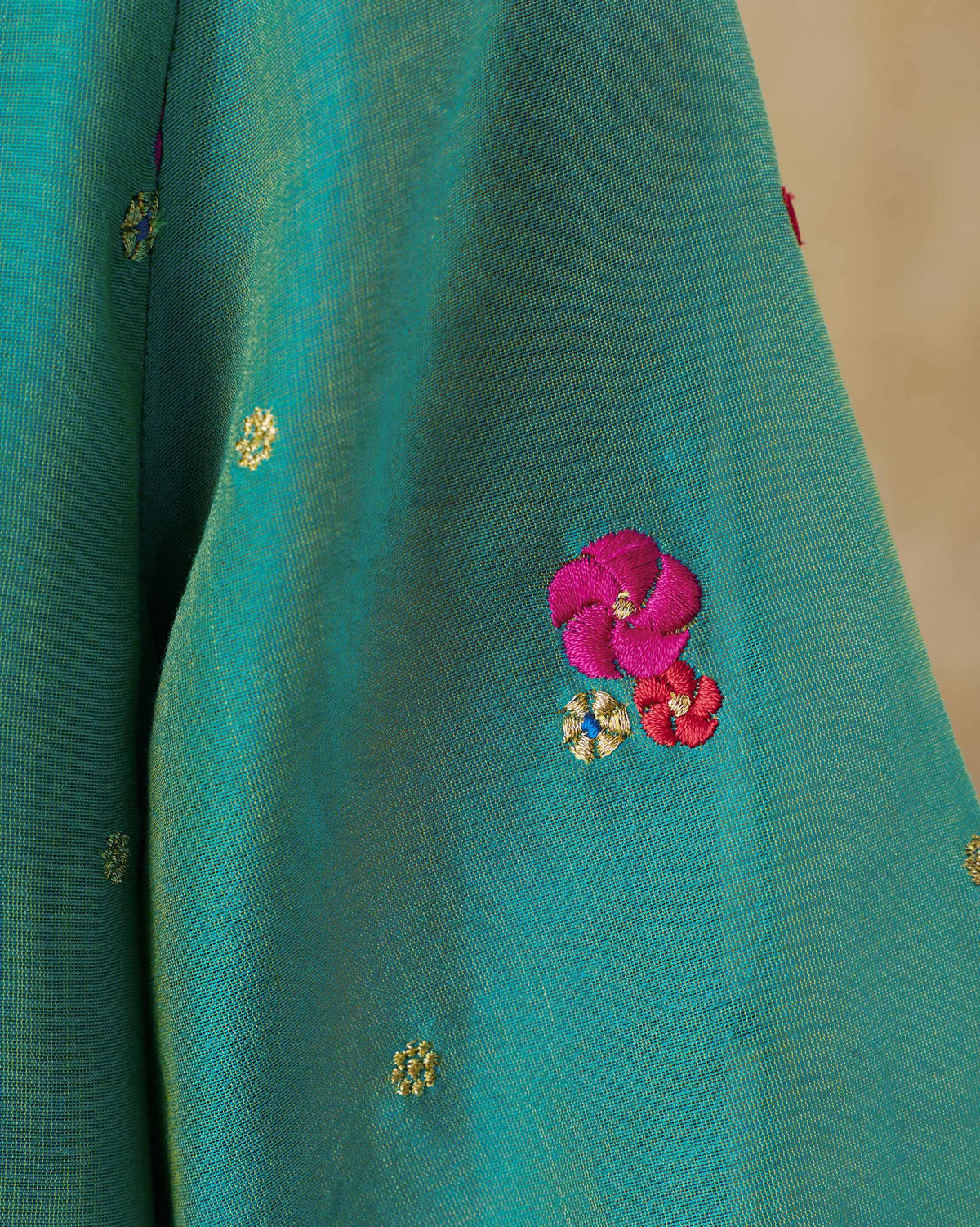 Close-up of an aqua Twilight kurta showing pink and red embroidered flowers.