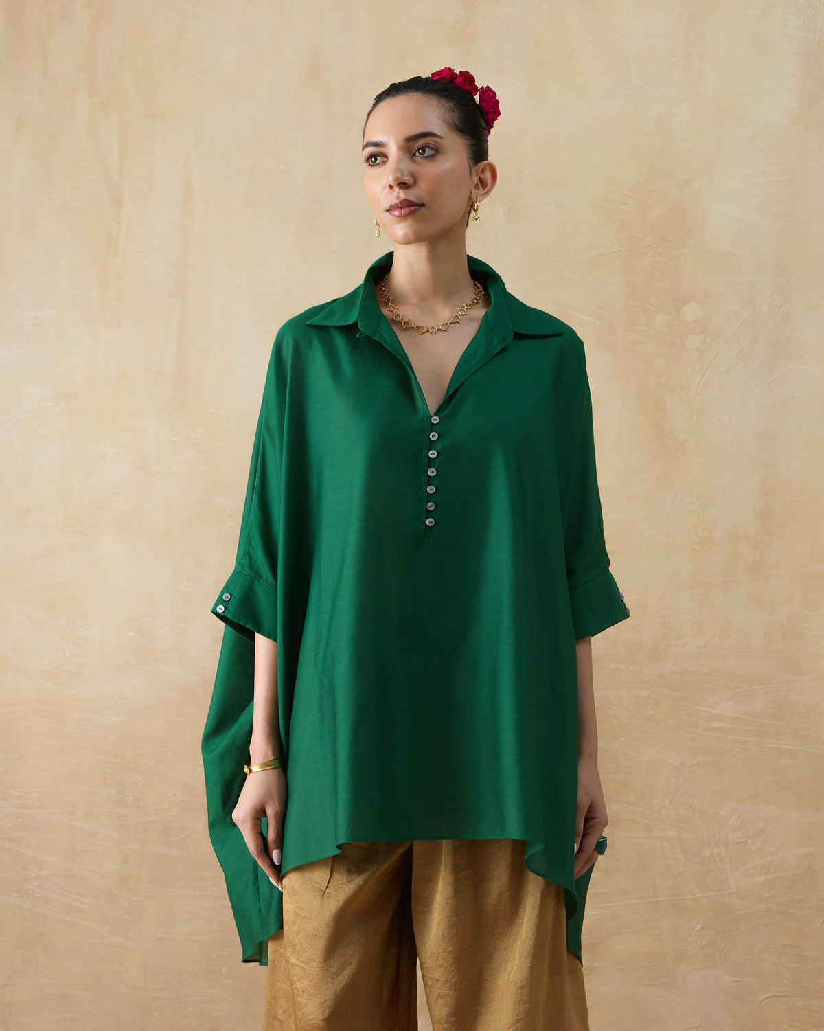 Person wearing an emerald green Hala tunic with a shirt collar and loose sleeves.