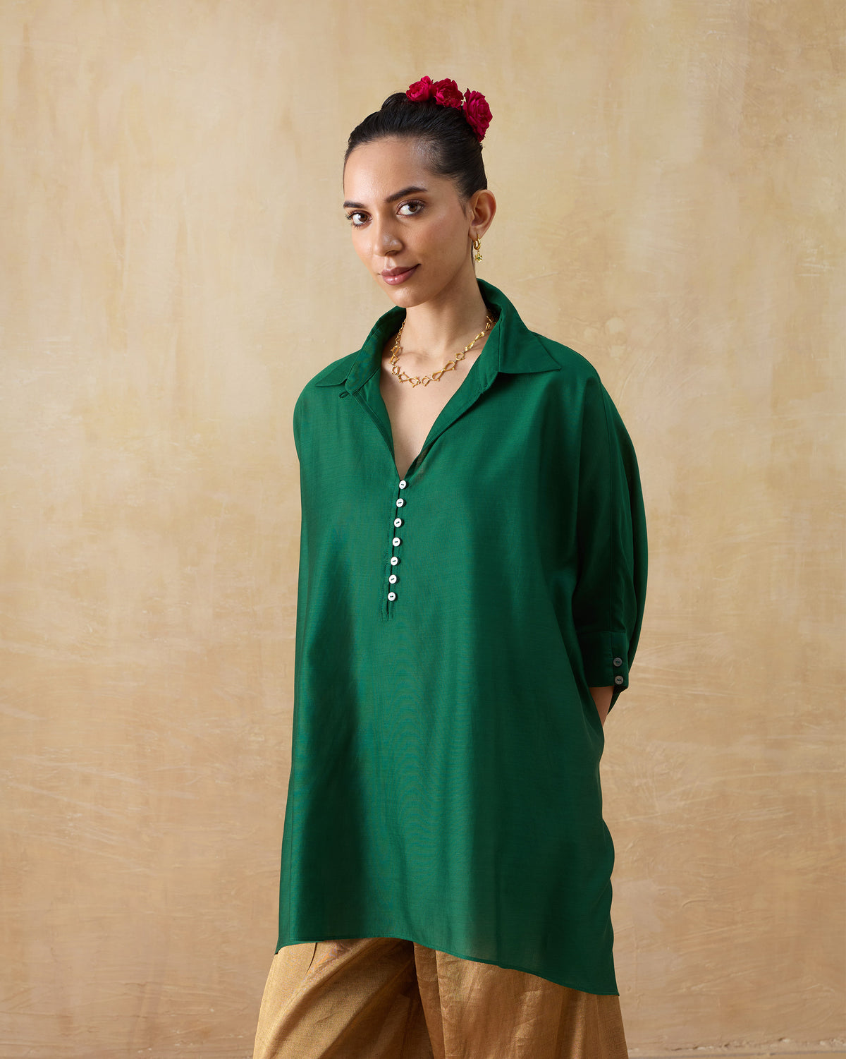 Person wearing an emerald green Hala tunic with a button placket and cuffed sleeves.