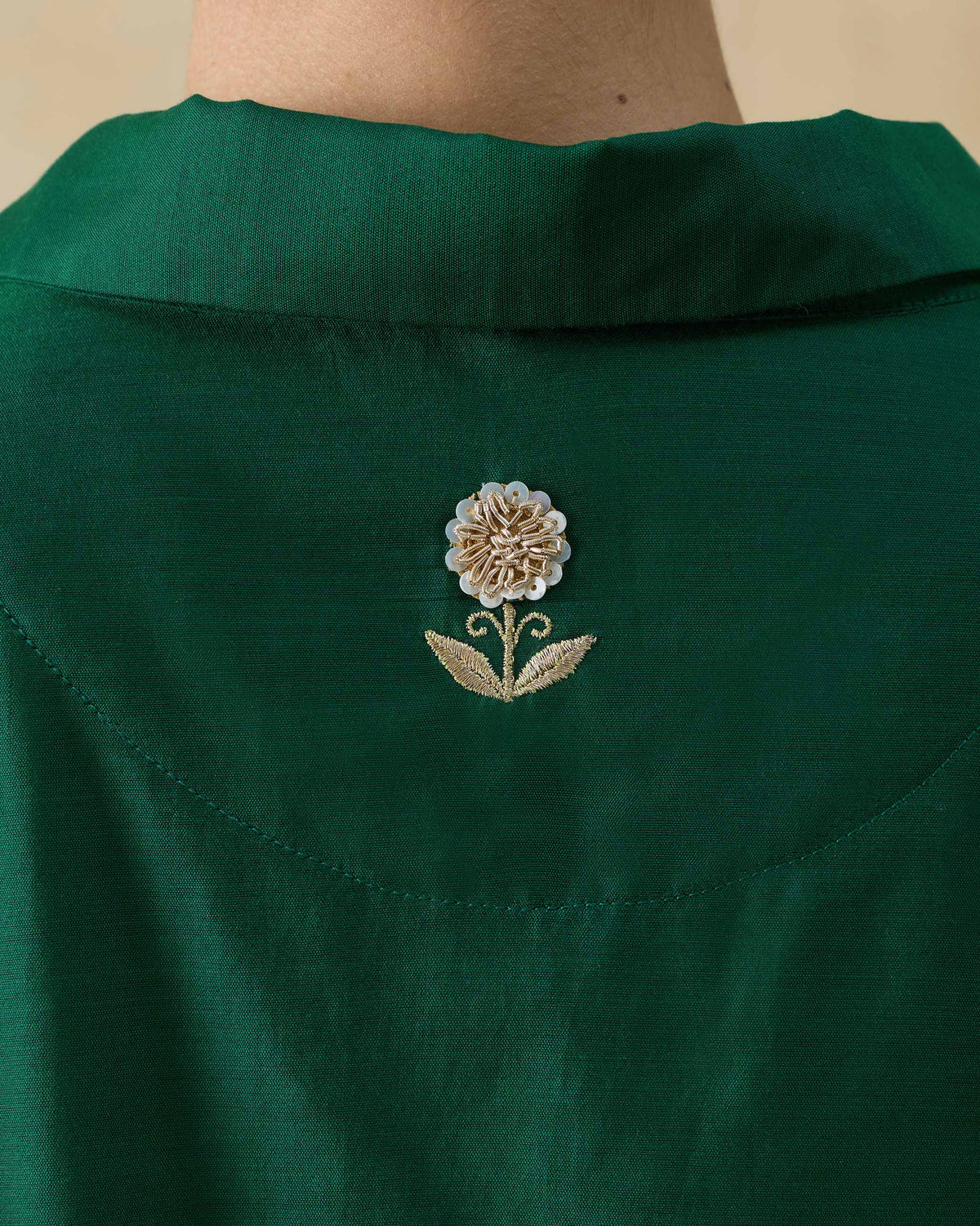 Close-up of a gold zarsozi flower on the back of an emerald green Hala tunic.