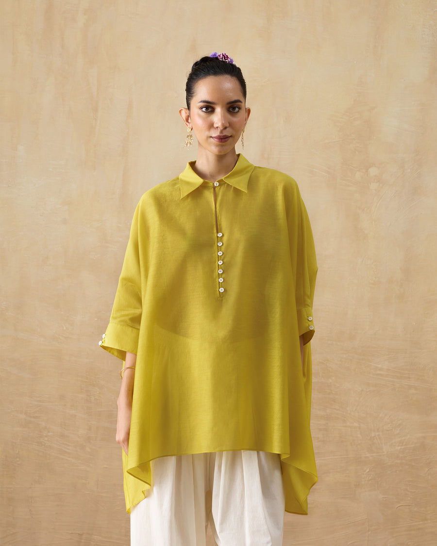 The Hala Tunic, a loose chartreuse cotton silk tunic with a shirt collar and kaftan sleeves, worn over ivory trousers.