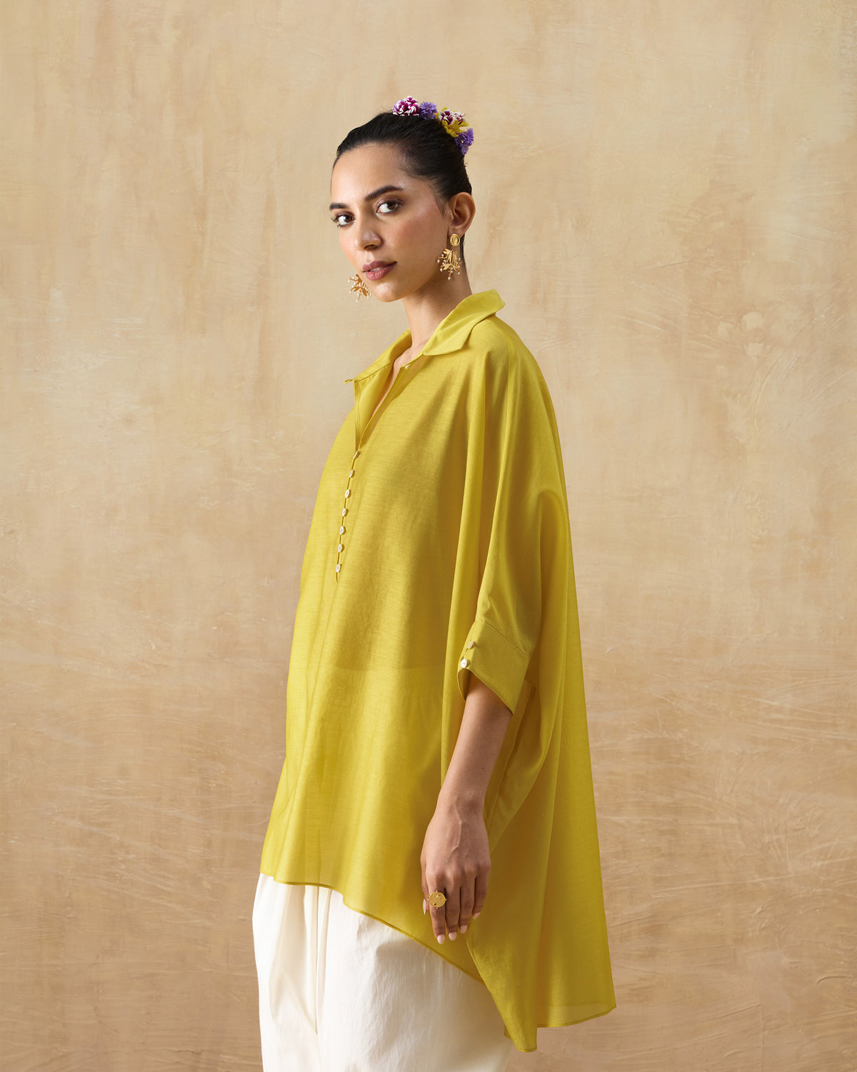Person wearing a chartreuse oversized tunic with wide sleeves.