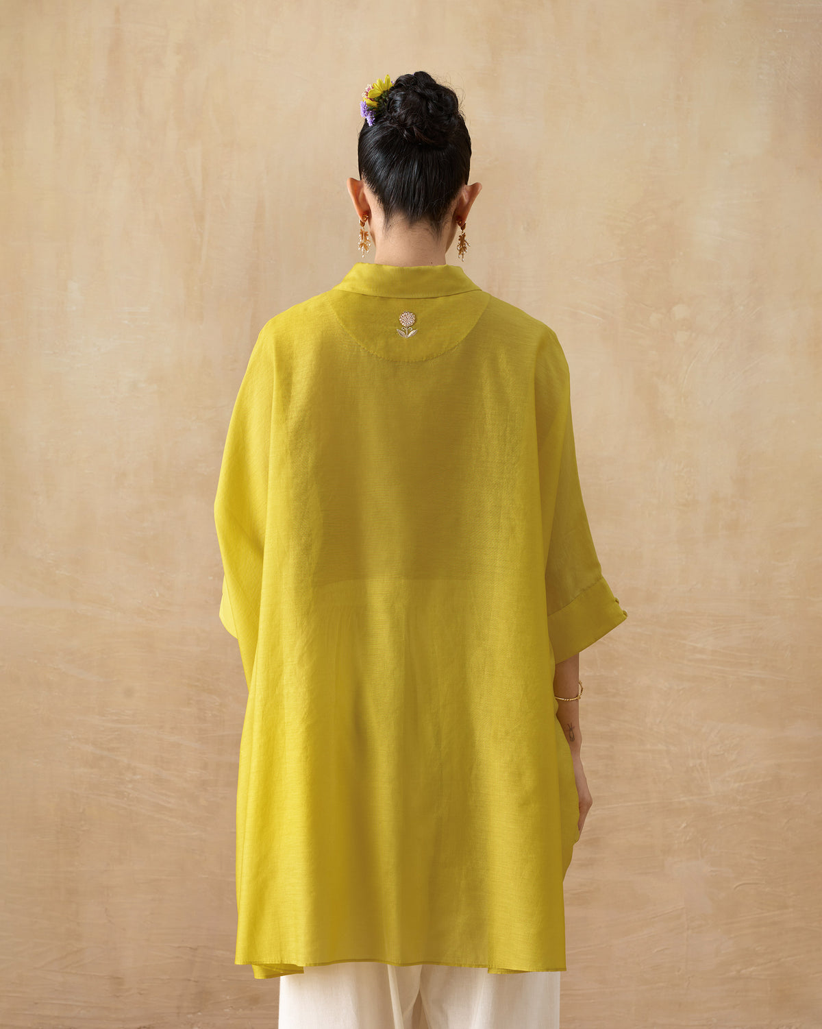Back of a chartreuse tunic with a small floral motif on the yoke.