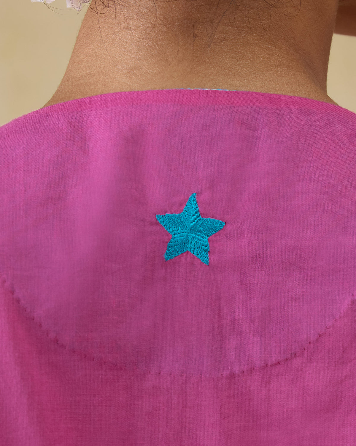 Close-up of an aqua embroidered star on a bright pink Pintuck kurta.