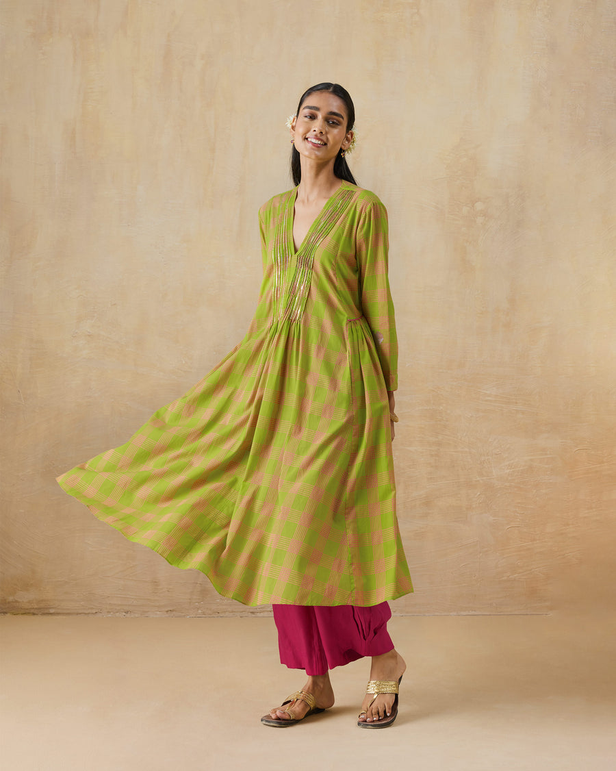 The Pintuck Kurta, a fuchsia and lime checked cotton kurta with a pintucked V-neck, its gathered panels swinging out, worn over pink trousers.
