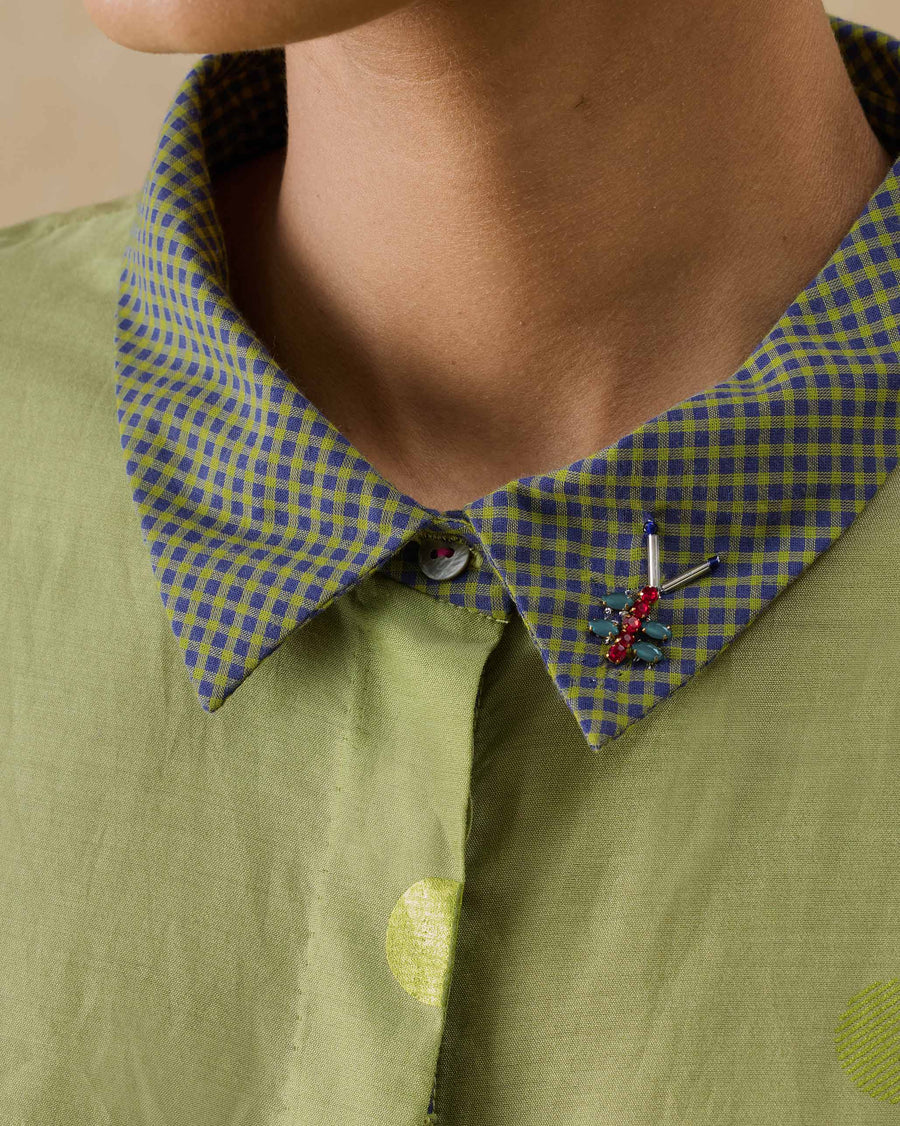 Close-up of the Strut Kaftan's collar, with a red and aqua stone bug embroidery and a fuchsia thread button.