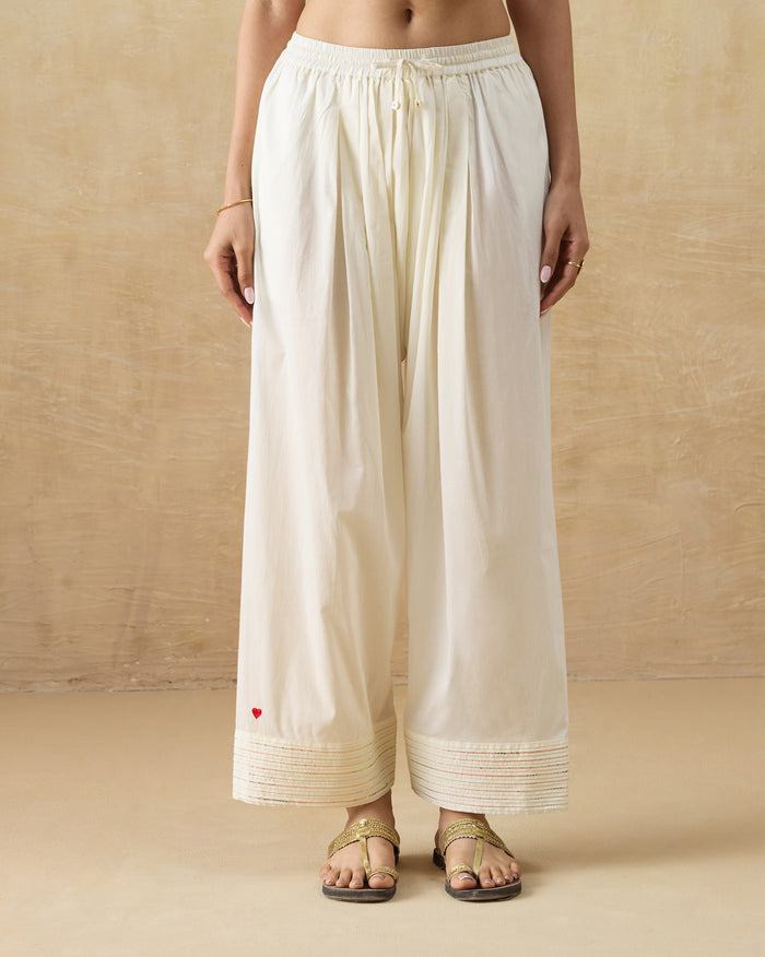 Person wearing ivory Numa Pants with a sequin pintuck hem.