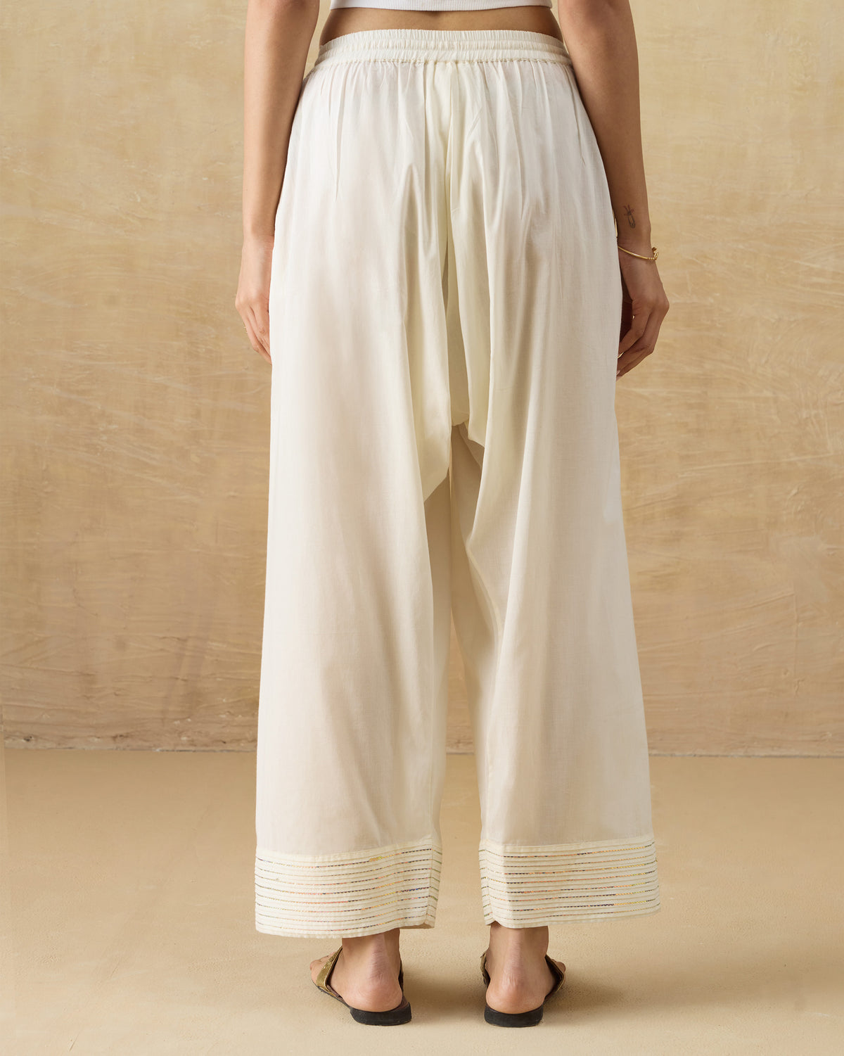 Back of ivory Numa Pants with a wide sequin pintuck hem.