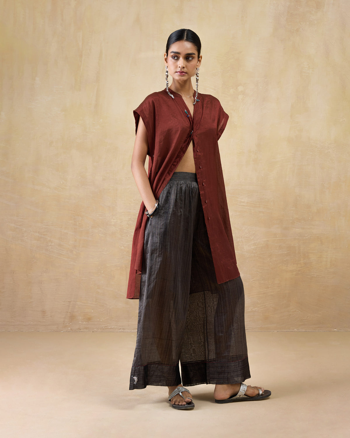 Person wearing a long scarlet red metallic tissue kaftan with a V-neckline.