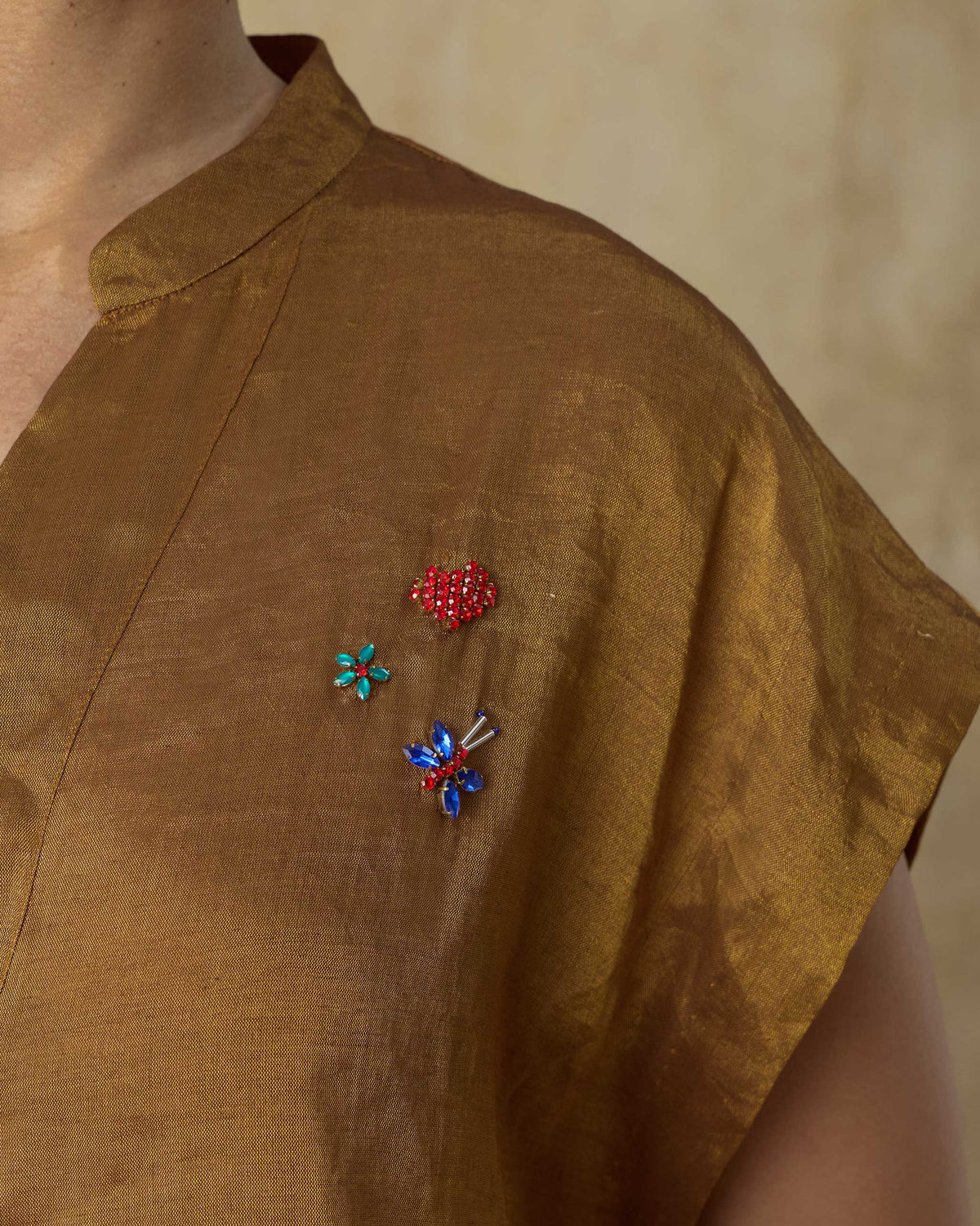 Close-up of jewelled berry, flower, and dragonfly motifs on a gold Tango kaftan.