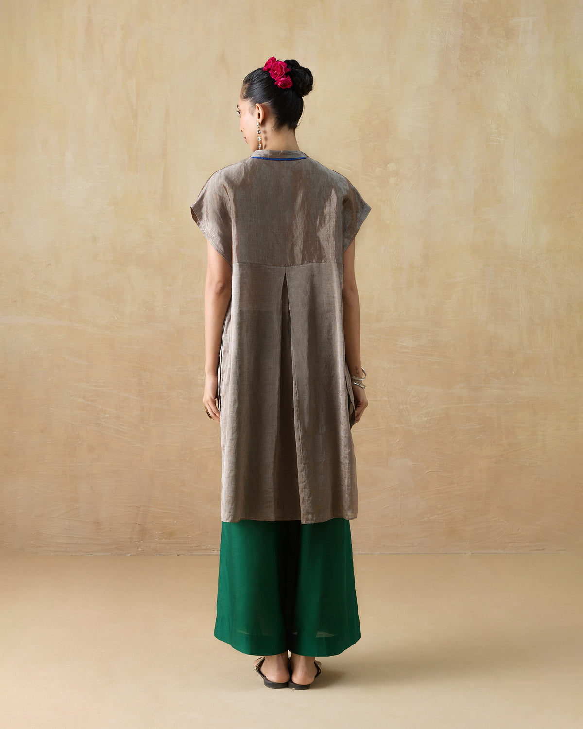 Back of a silver metallic kaftan with a box pleat and blue neck trim.