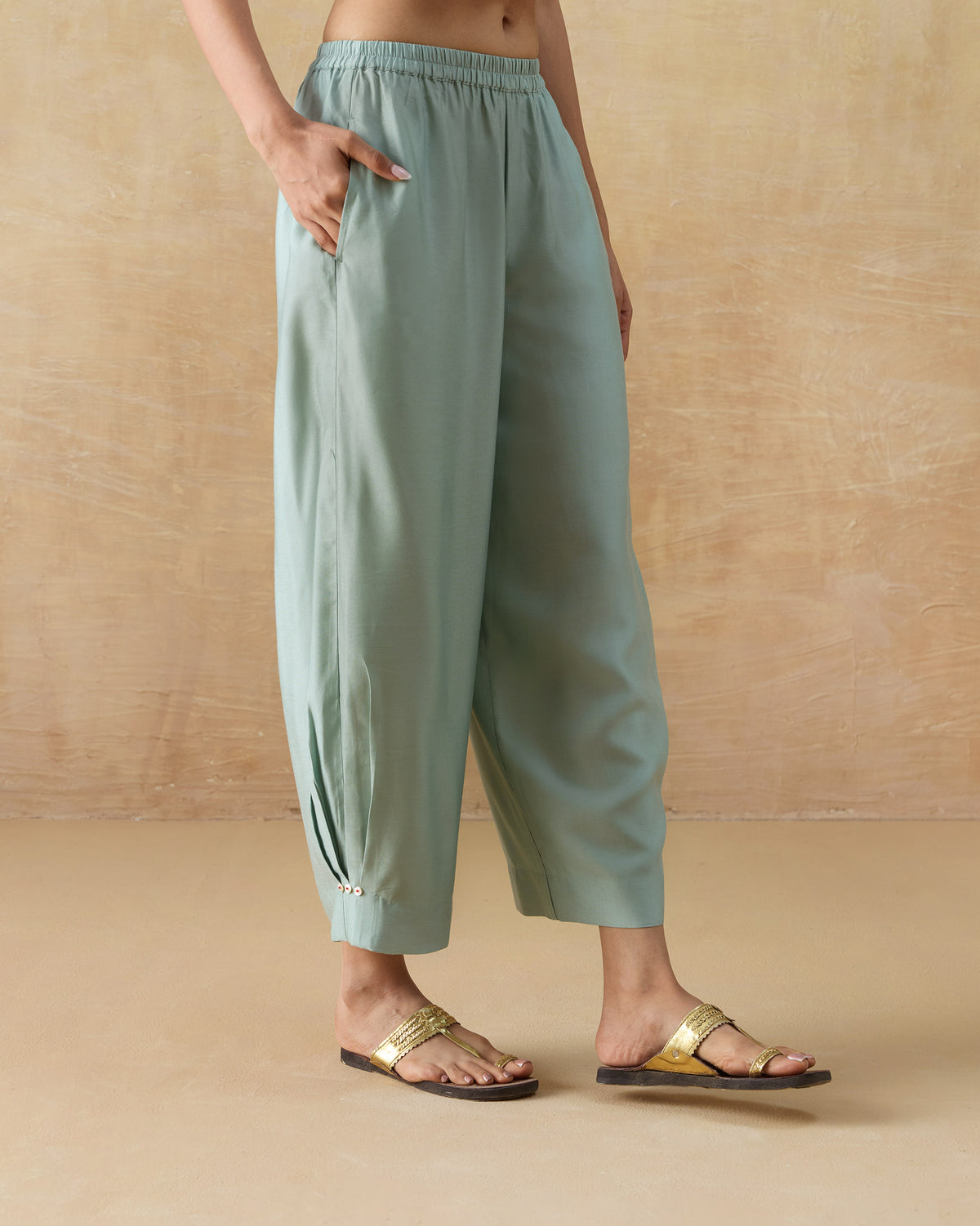 Side view of pale green Wander Pants showing the side pocket and tapered leg.