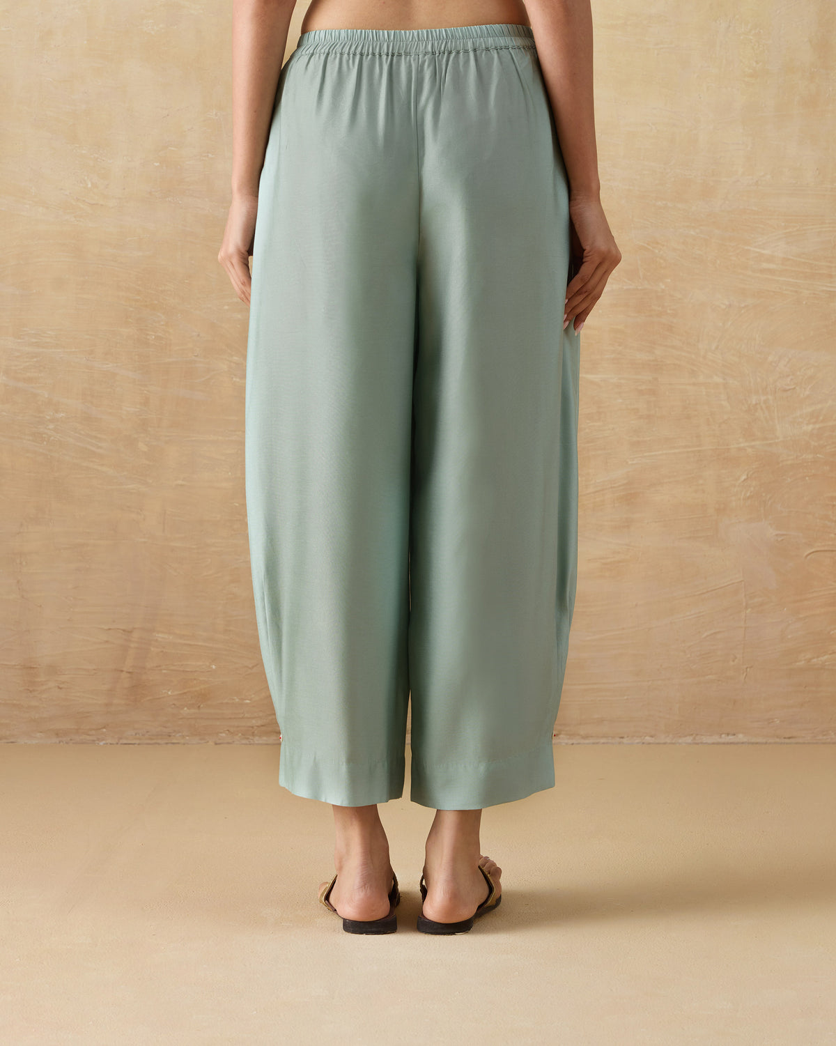 Back of pale green Wander Pants with an elastic waistband worn by a person.