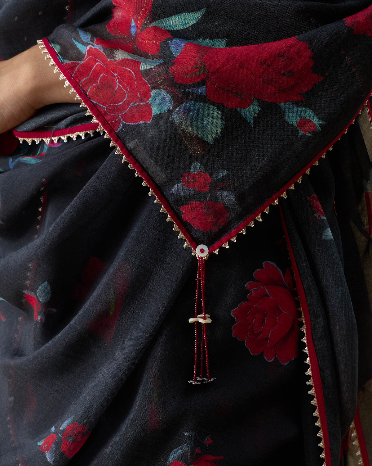 Close-up of a Fizz dupatta showing red rose print and a beaded tassel.