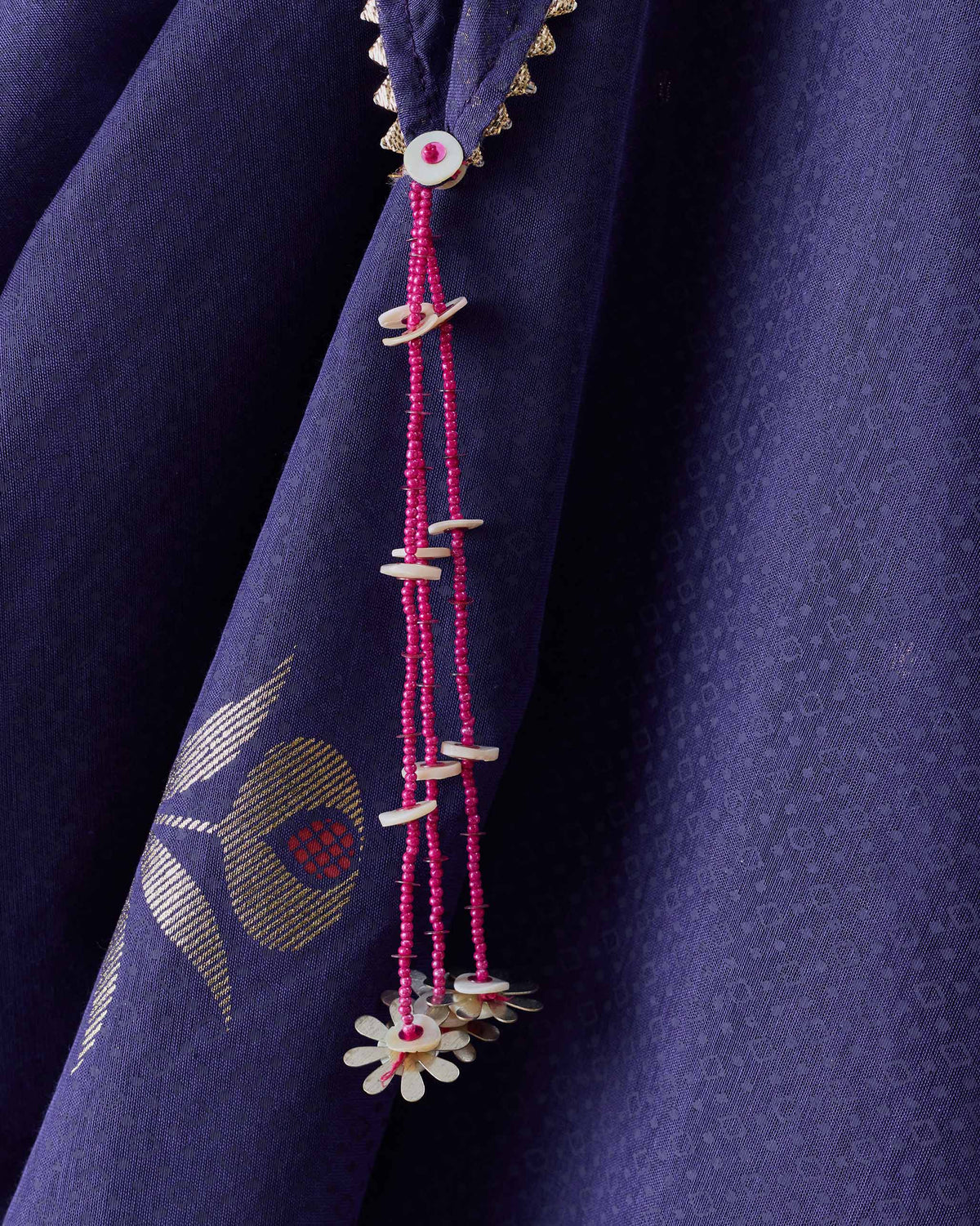 Close-up of a Buzz dupatta tassel with pink beads and white shell charms.