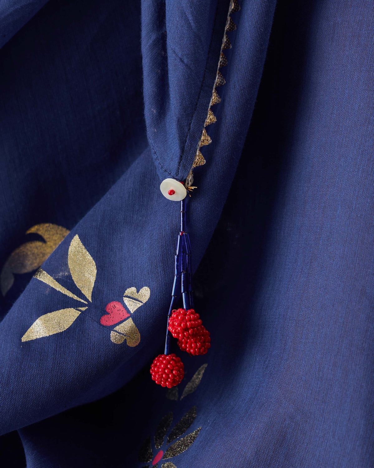 Close-up of Glowgetter Dupatta with gold motifs and a red beaded tassel.