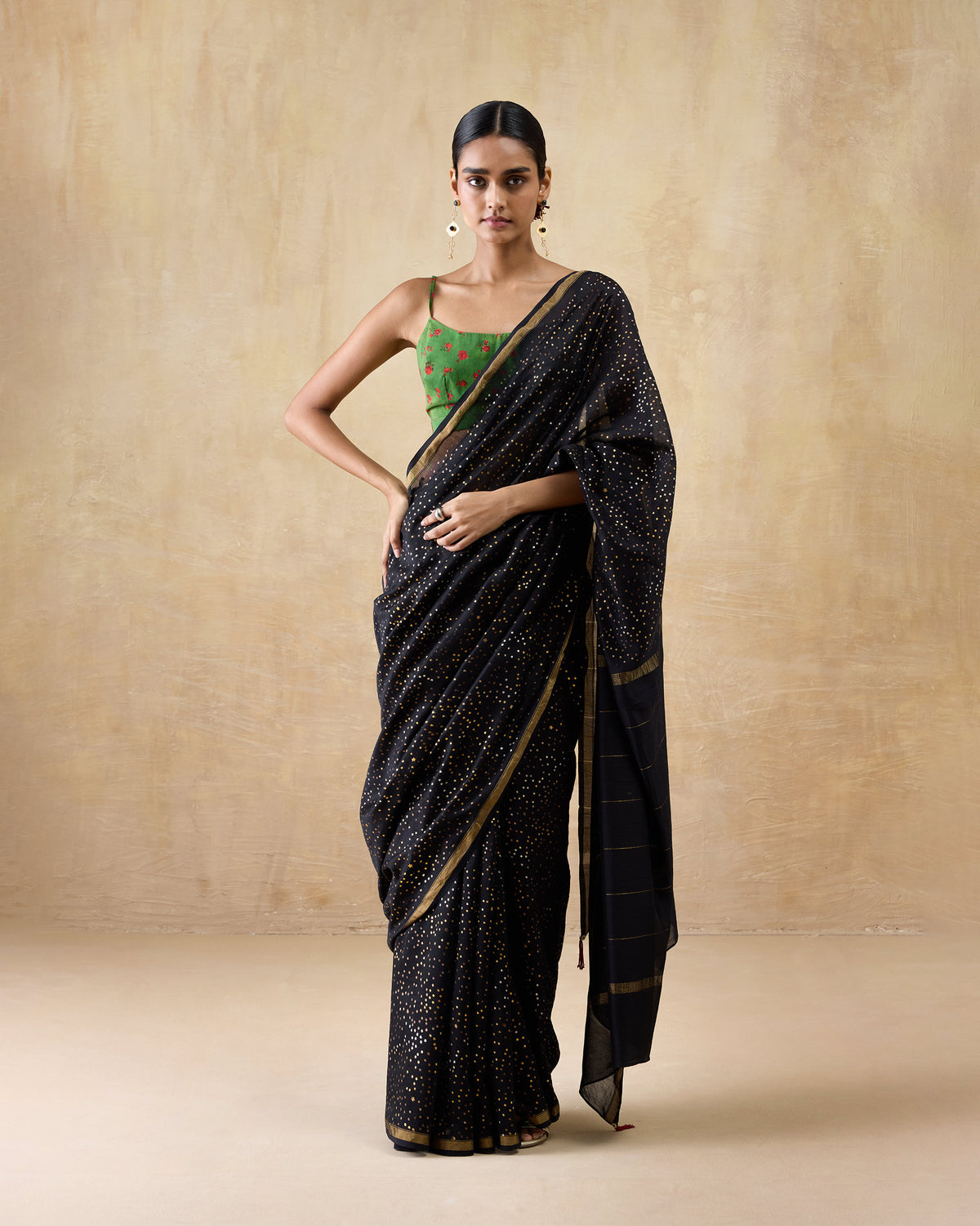 Person wearing a black and gold Riverbank sari with dense gold dots and a gold border.