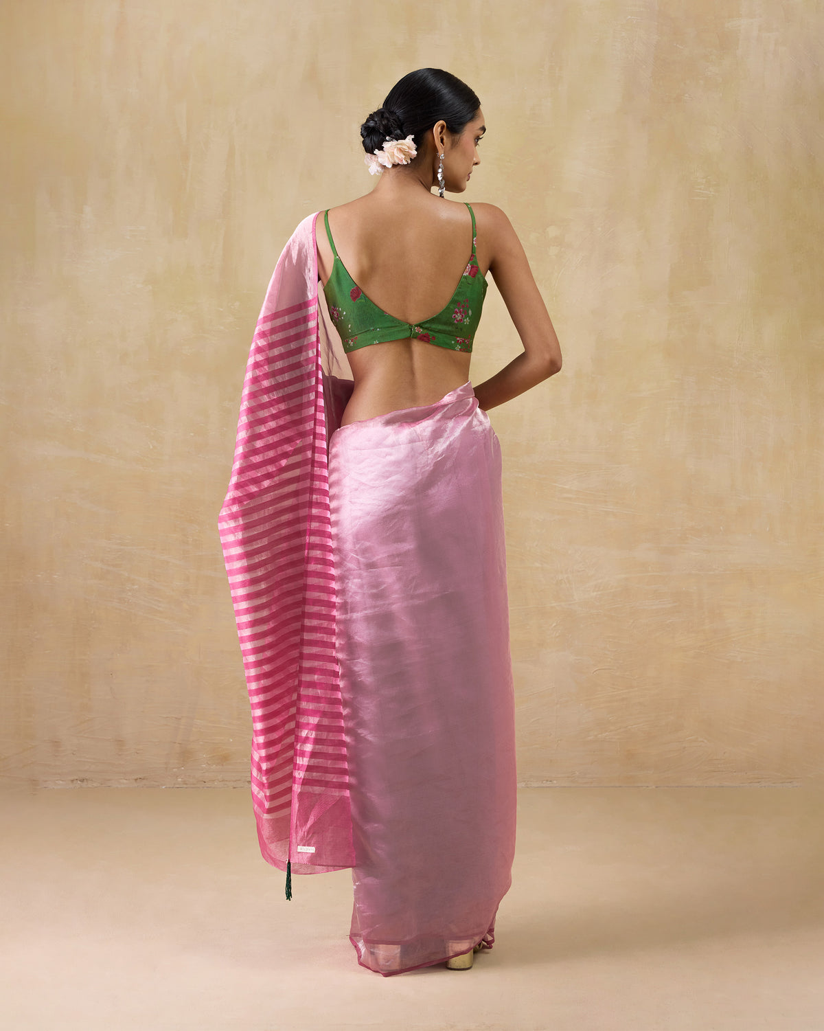 Back of a blush pink Blush sari with a striped pallu and green tassel.