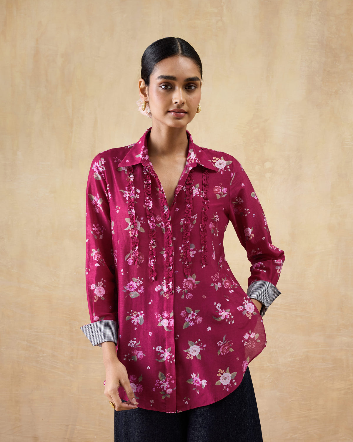 Person wearing a berry Kaveri ruffle shirt with floral print and front ruffles.