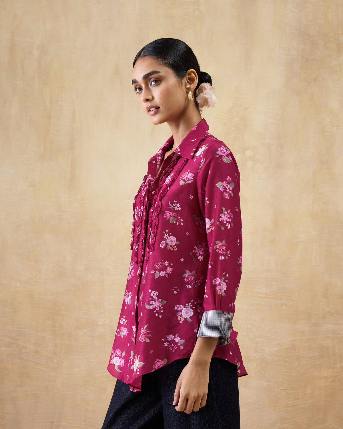 Person wearing a berry Kaveri ruffle shirt with floral print and frayed ruffles.