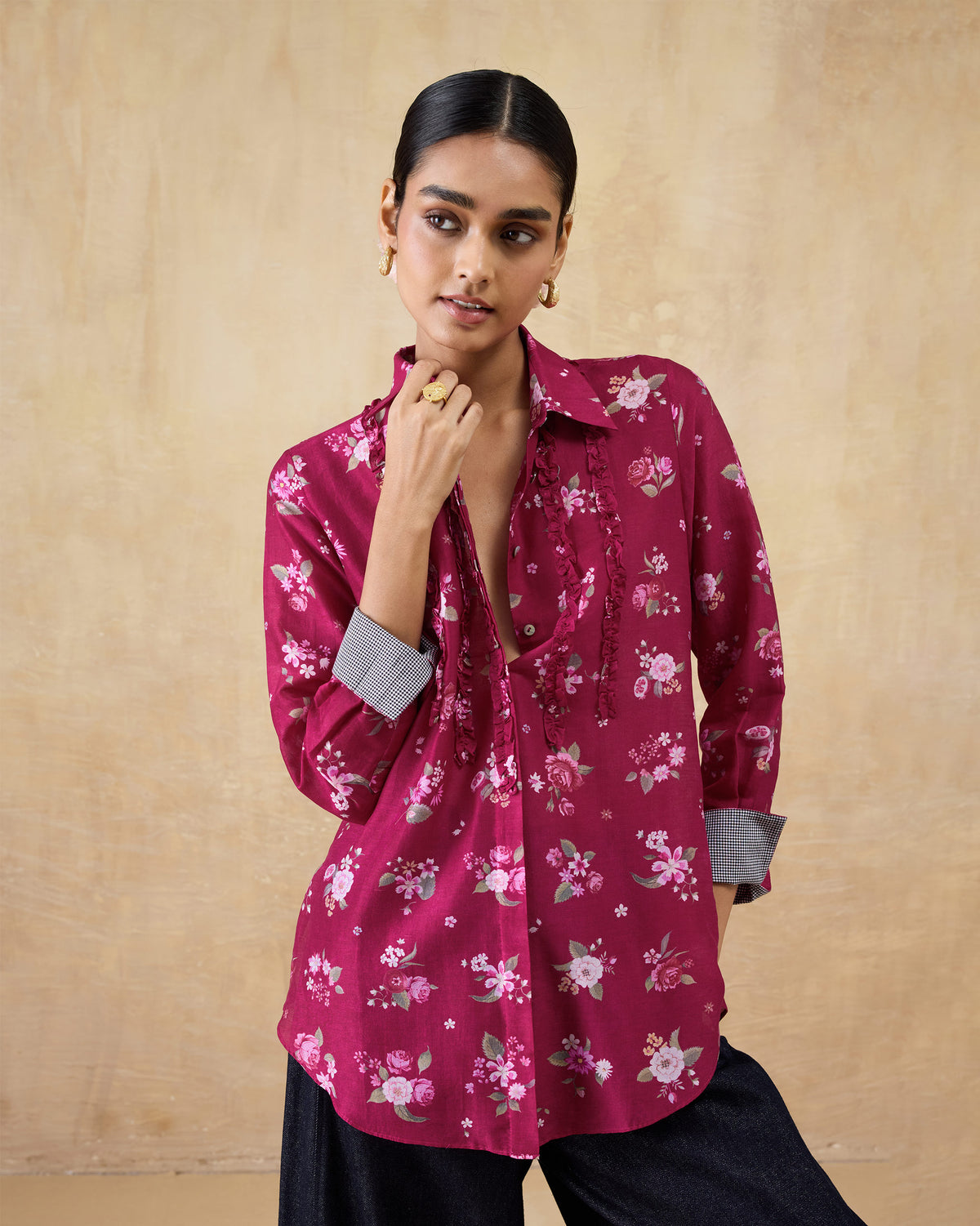 Person wearing a berry Kaveri shirt with front ruffles and contrast cuff lining.
