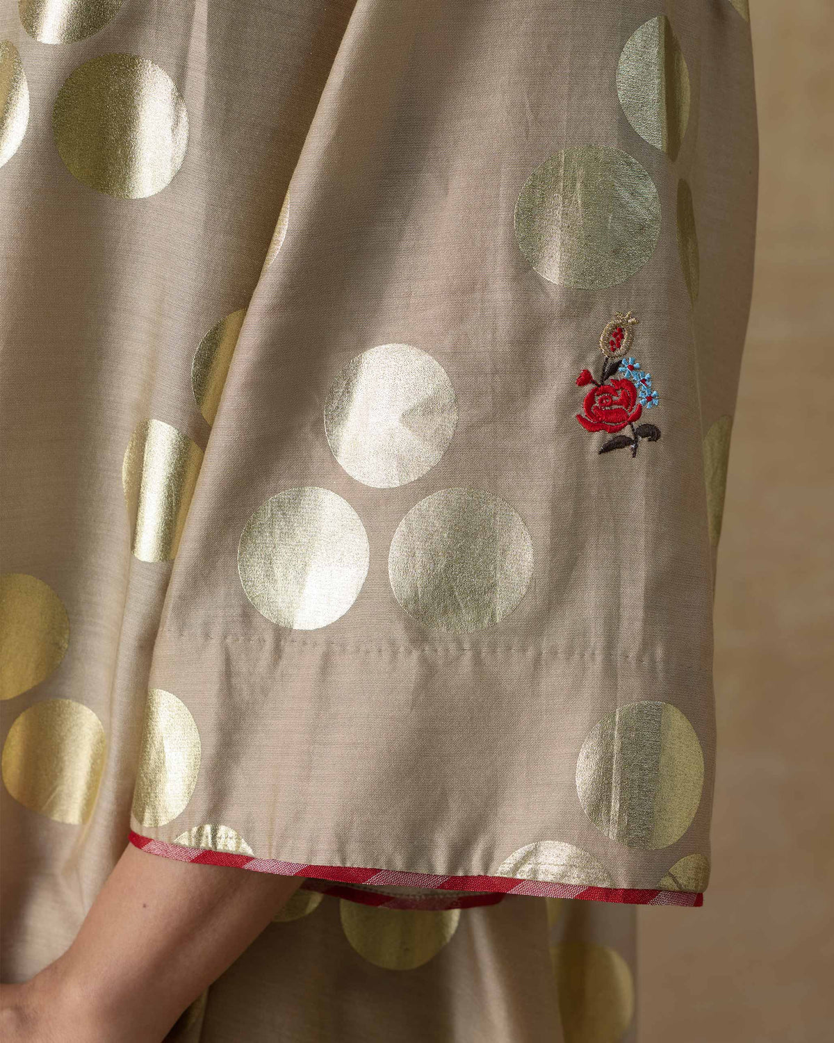 Close-up of a Cloud Dancer kurta sleeve with gold dots and floral embroidery.