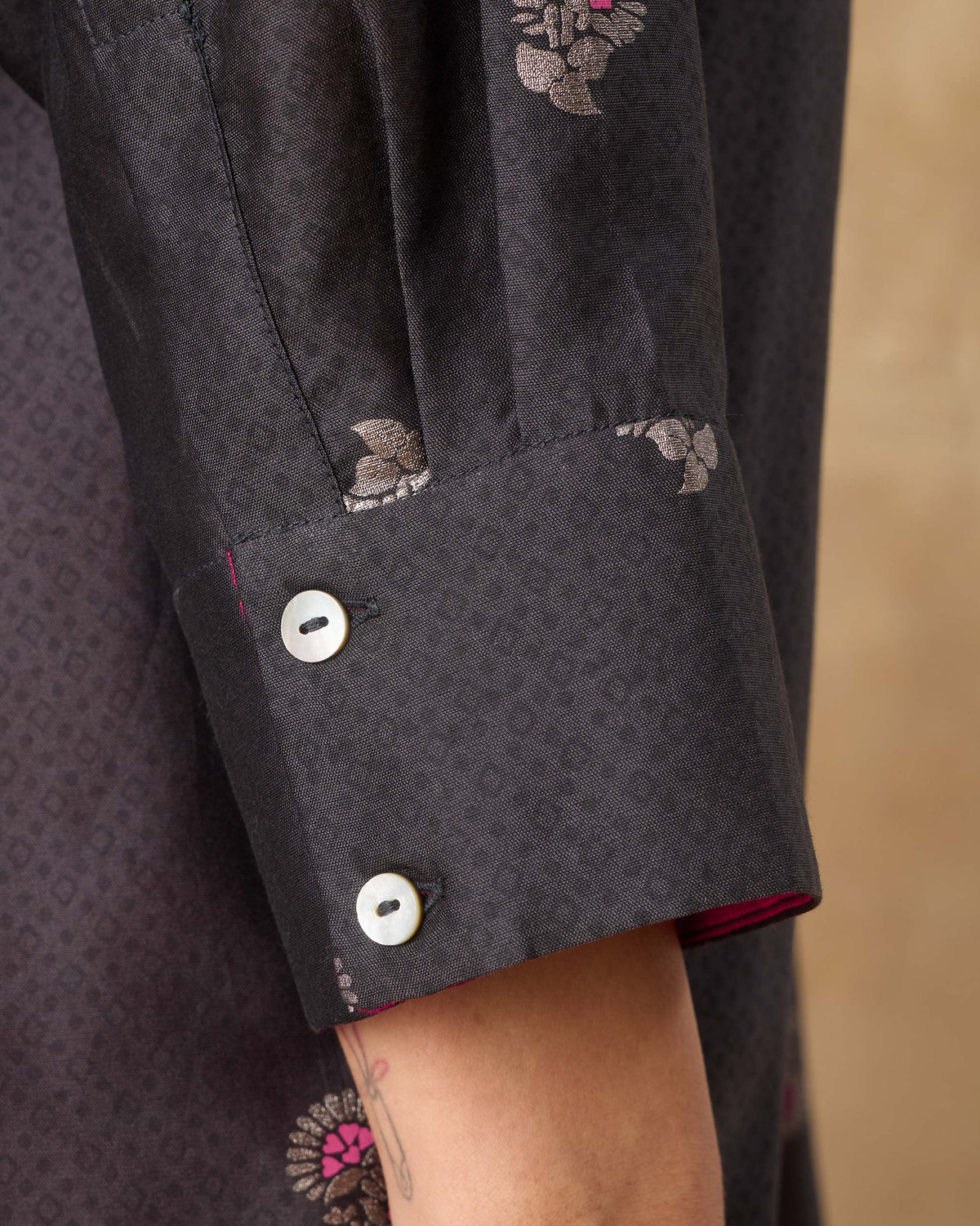 Close-up of the buttoned cuff and magenta lining on a charcoal Lazy Sunday tunic.