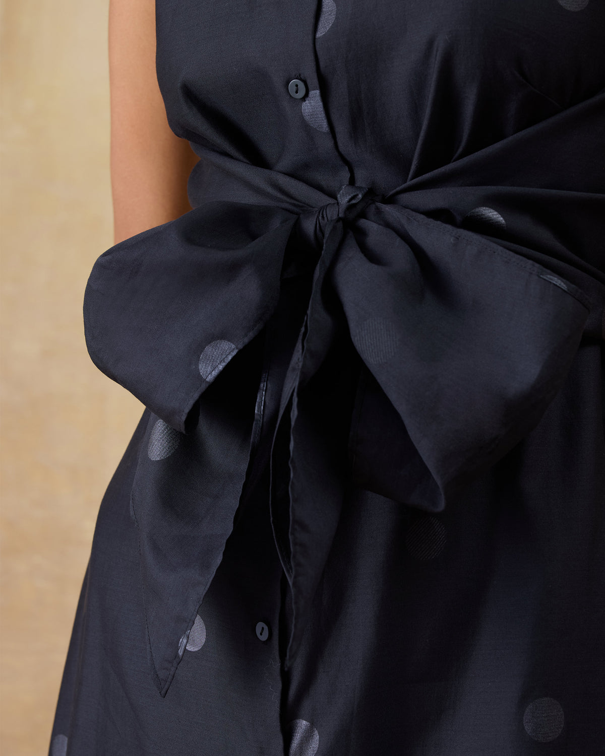 Close-up of the waist bow on a black Sonnet dress.