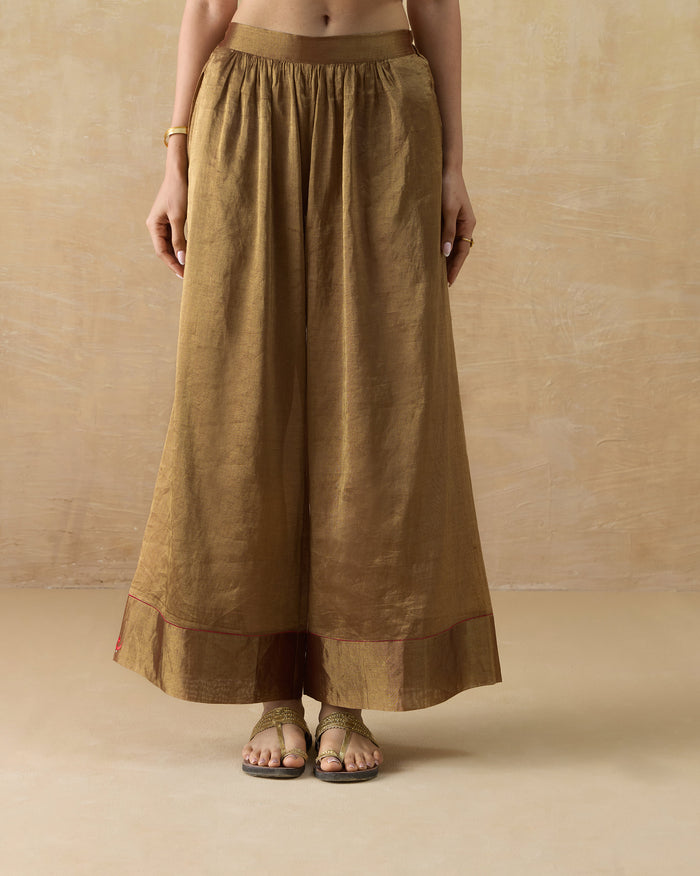 Gold metallic Charisma pants with a wide A-line leg and bordered hem.