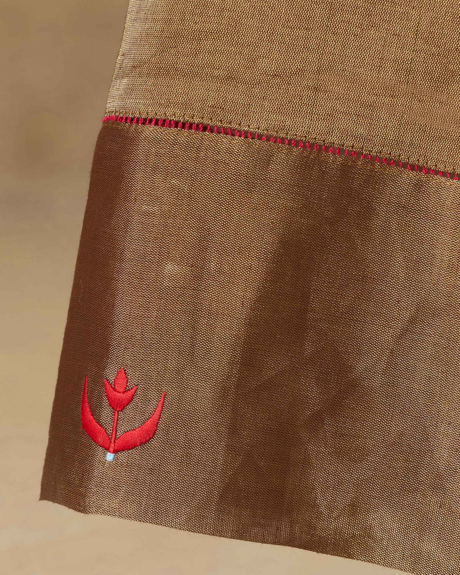 Close-up of the hem of the Charisma Pants, with red fagotting above an embroidered red tulip.