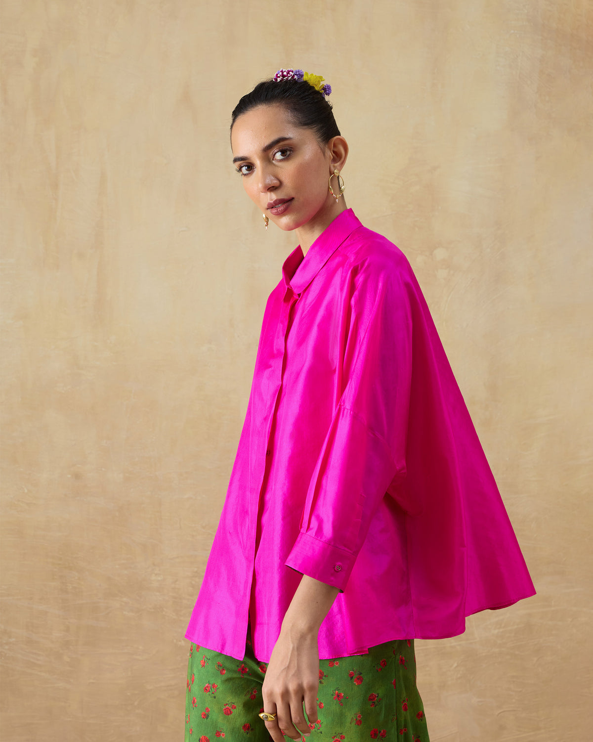 Side view of a fuchsia pink silk boxy shirt showing the loose flared silhouette.