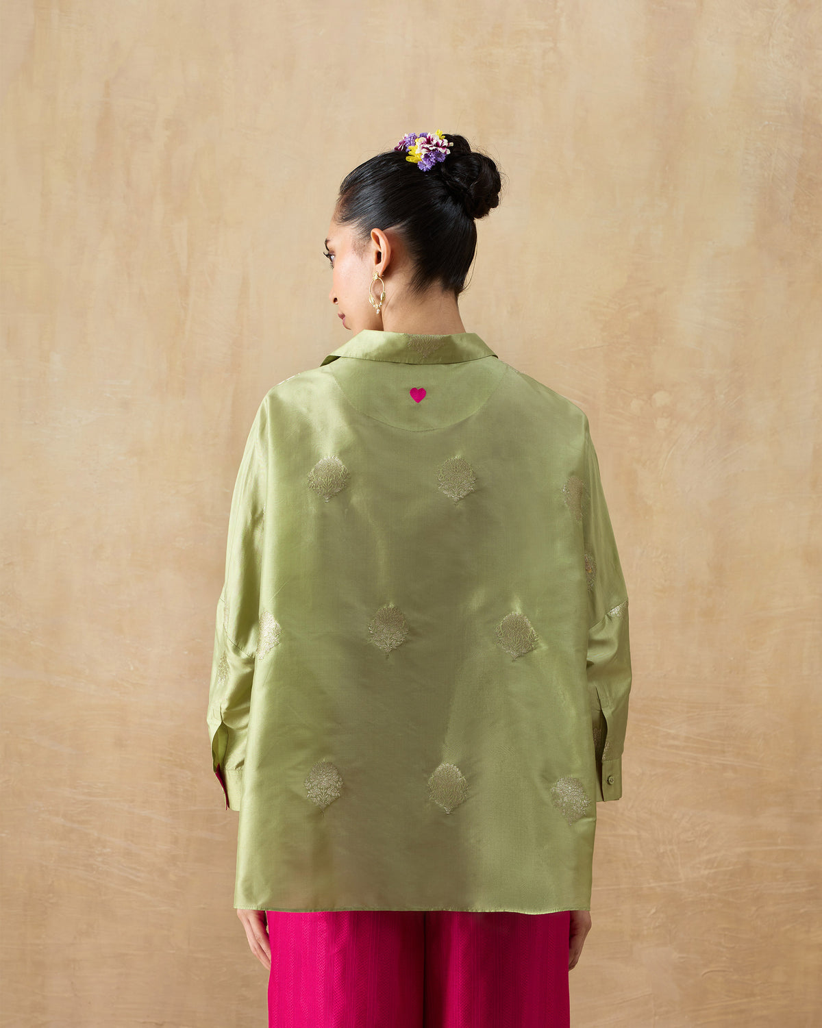 Back of a leaf green Boxy shirt with a small pink heart.