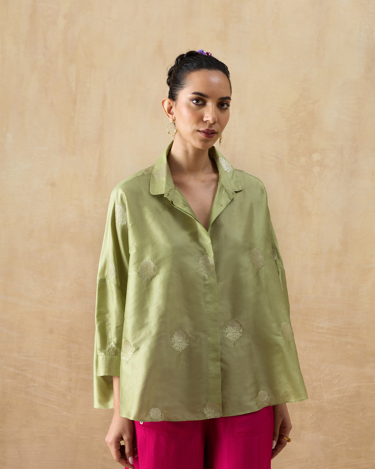 Person wearing a leaf green Boxy shirt with scattered silver buttas.