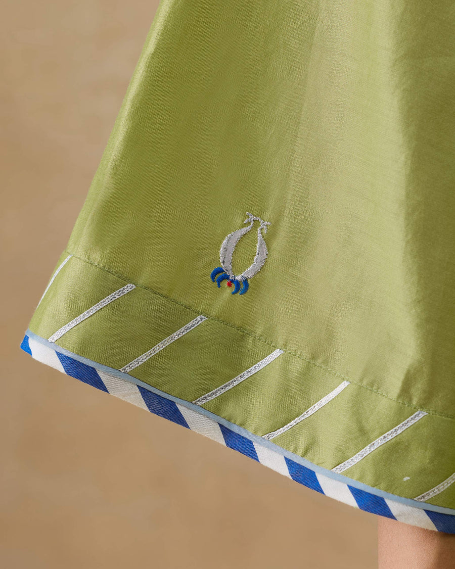 Close-up of the sleeve hem of the Revelry Kurta, edged in blue and white striped tape beside an embroidered anar.