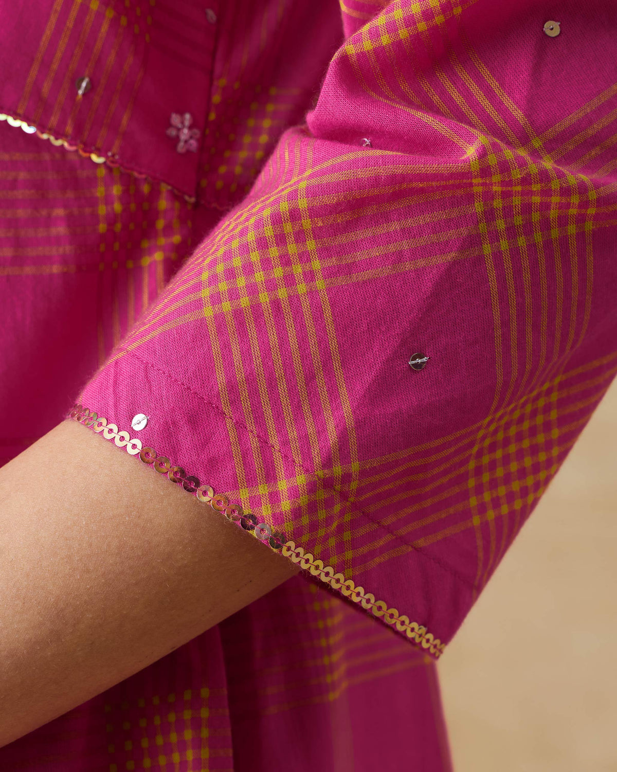 Close-up of a sequin-trimmed sleeve on the berry and lime check Drifter kurta.