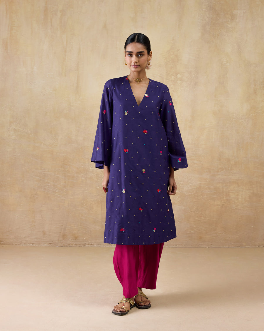 The Nebula Kurta, a long purple cotton silk kurta with a V-neck and all-over floral embroidery, worn over pink trousers.