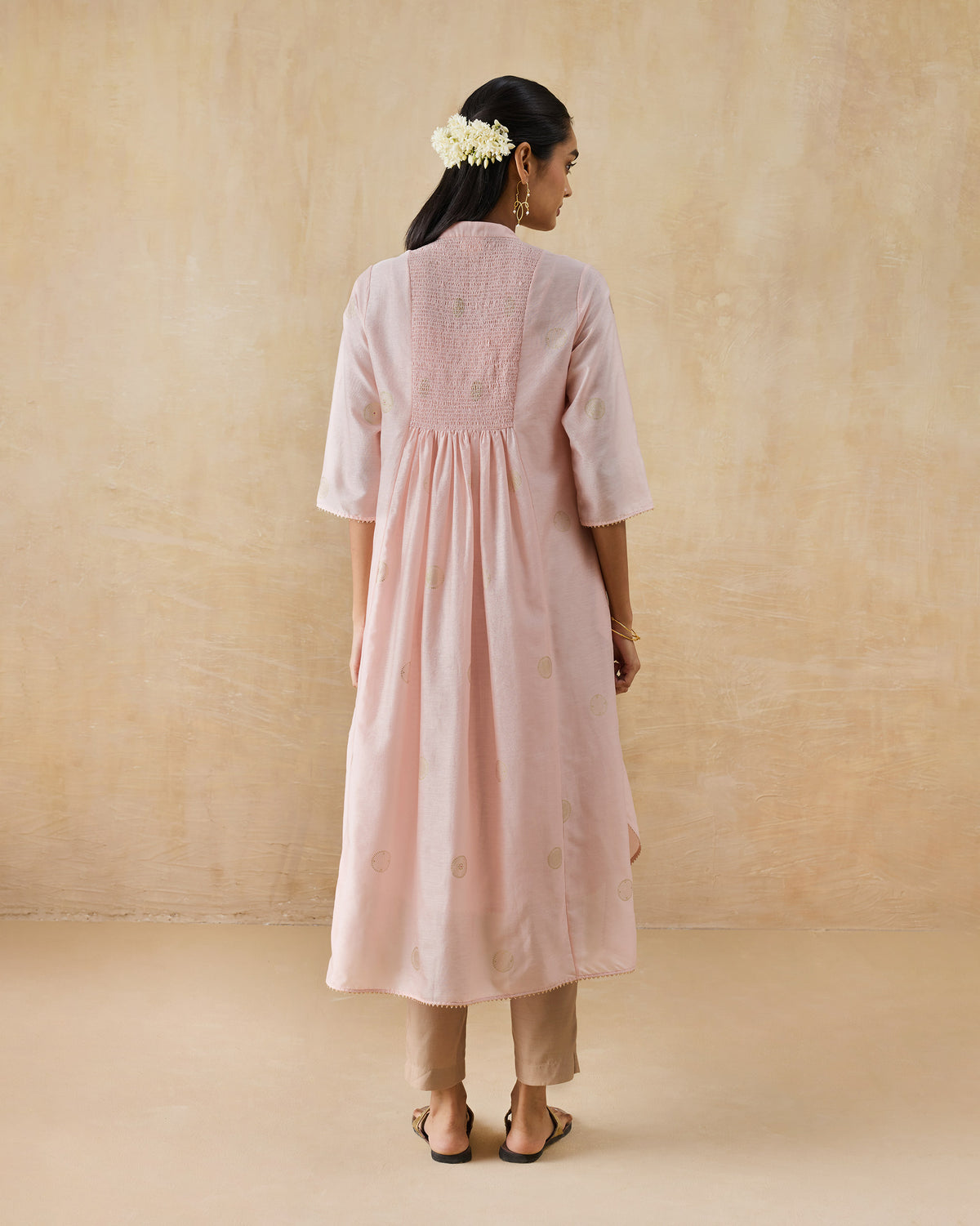 Back of a soft pink Radiant kurta with a smocked panel and gold dots.
