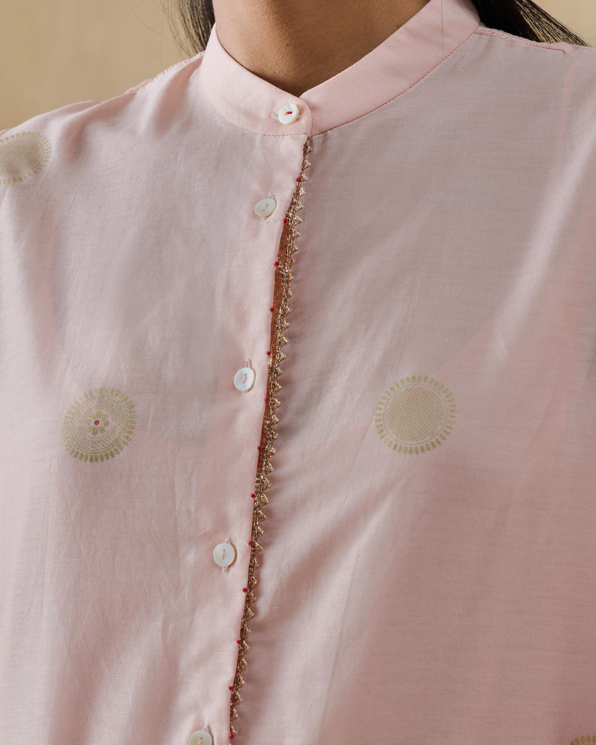Close-up of a soft pink Radiant kurta collar with gold lace trim and gold dots.