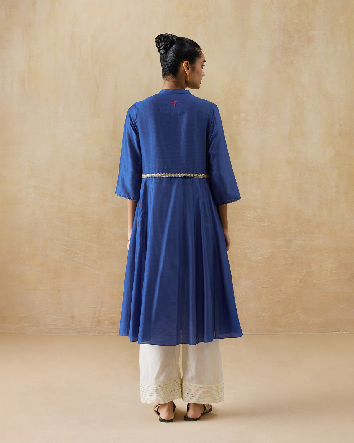 Back of a cobalt Moonsong kurta with a red motif at the neck.