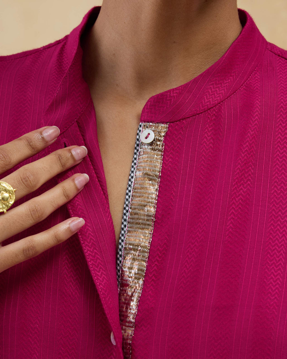 Close-up of gold placket embroidery on a berry pink mid-length kurta.