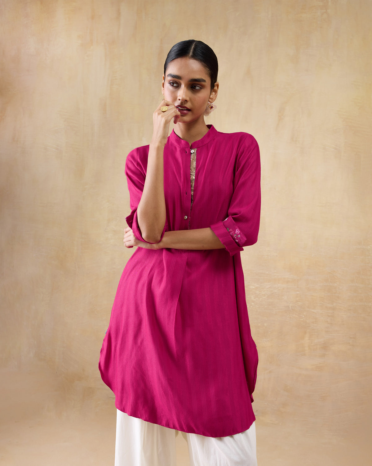Person wearing a berry pink mid-length kurta with a gold placket accent.