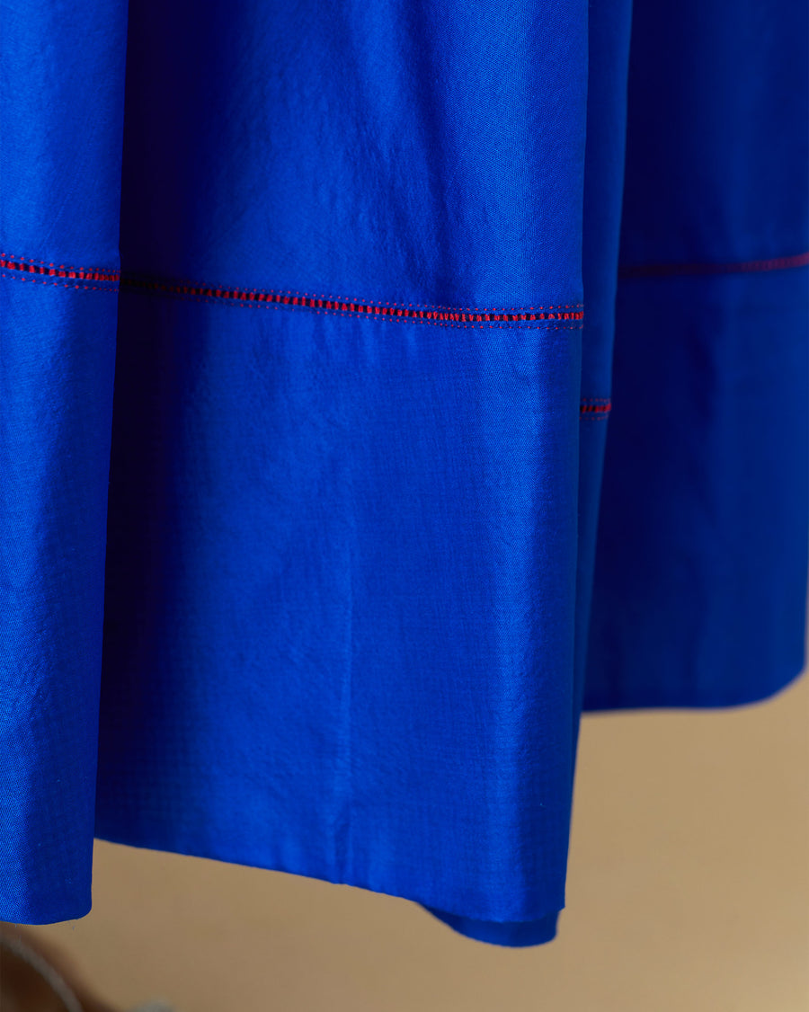 Close-up of the hem panel of the Akira Twist Back Dress, traced in red thread fagotting.